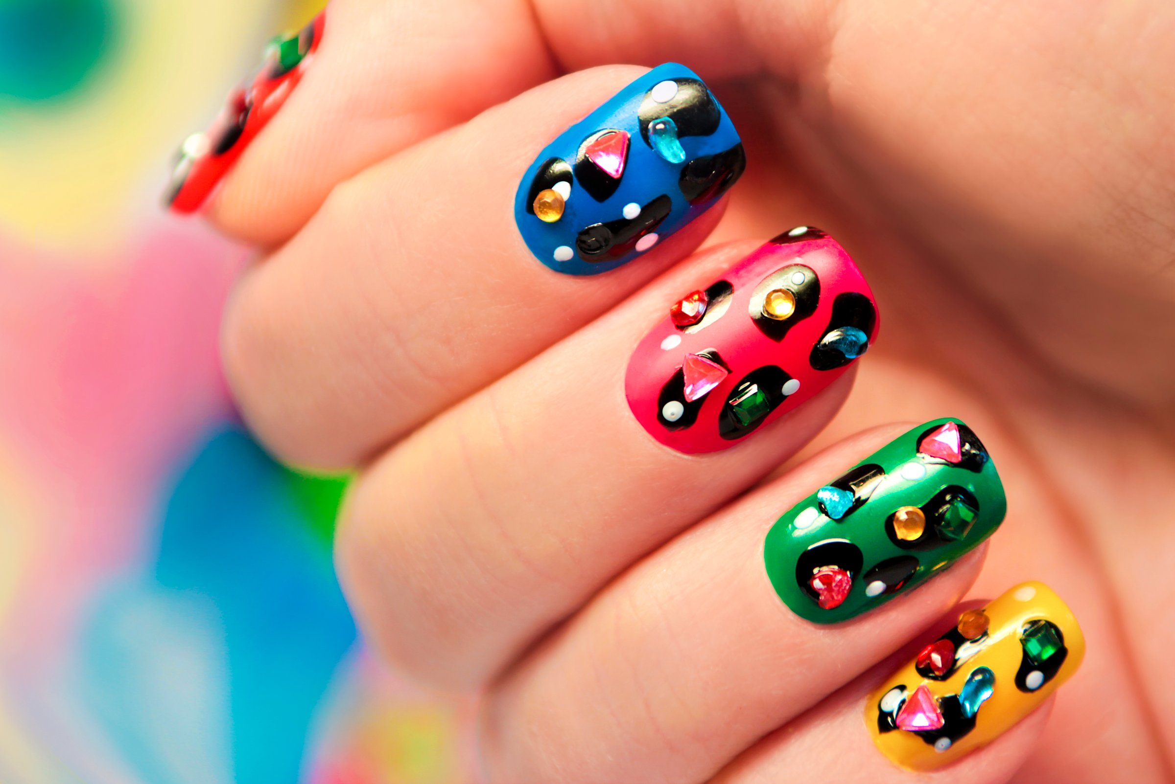 Multi-colored manicure with dots and rhinestones close-up.
