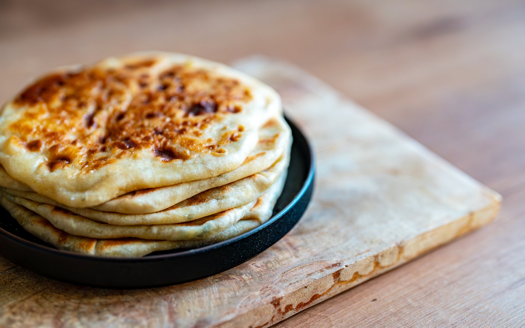 Freshly baked flatbreads served on wooden board.