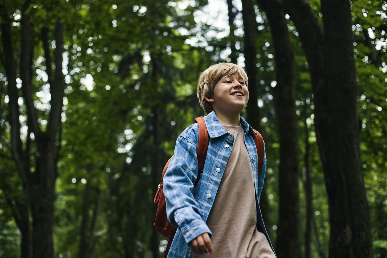 Boy walking through forest smiling during family road trip