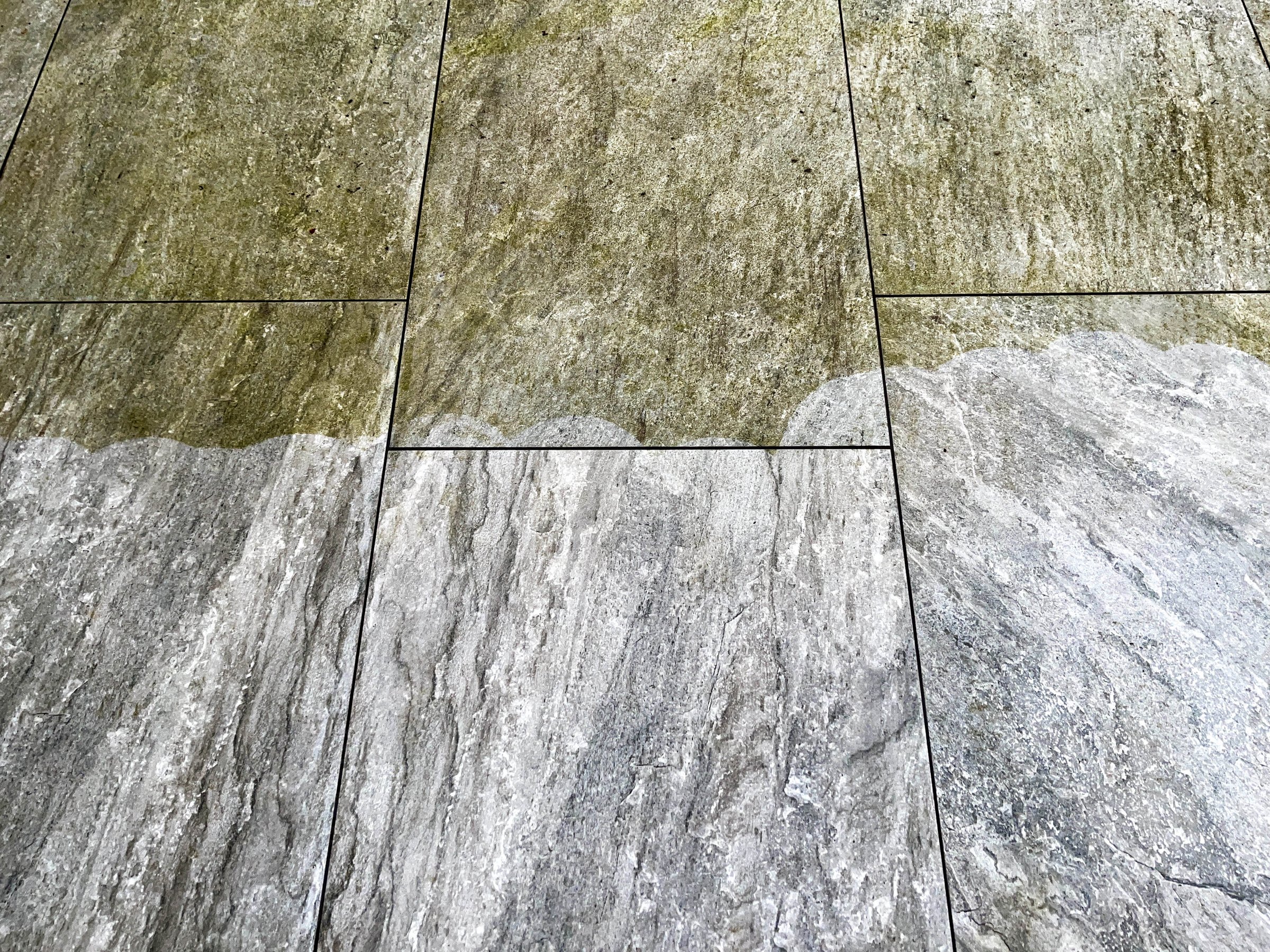 Contrast between the clean and dirty paving slabs on a garden patio after pressure washing. No people. Copy space.