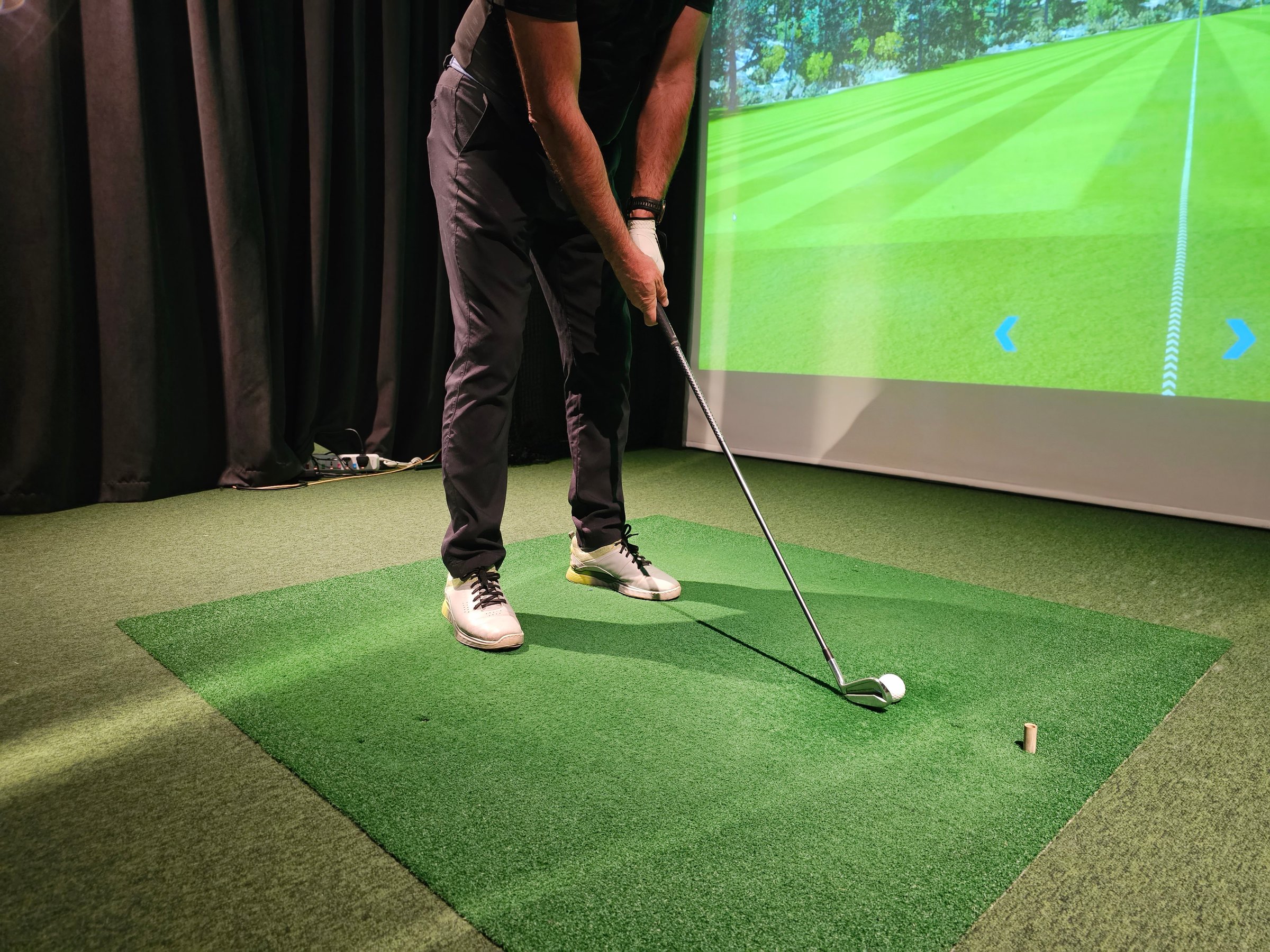 Indoor golf training session with player preparing to take a swing at a virtual course