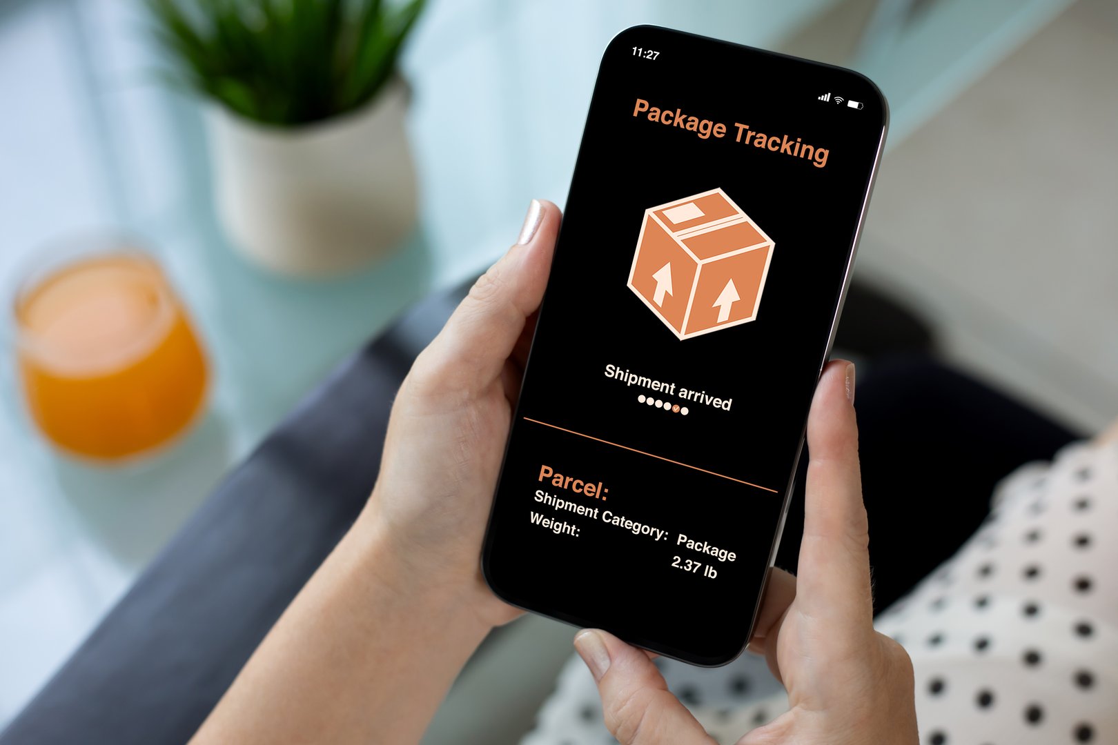 woman hands holding phone with app tracking delivery package on screen background of cafe