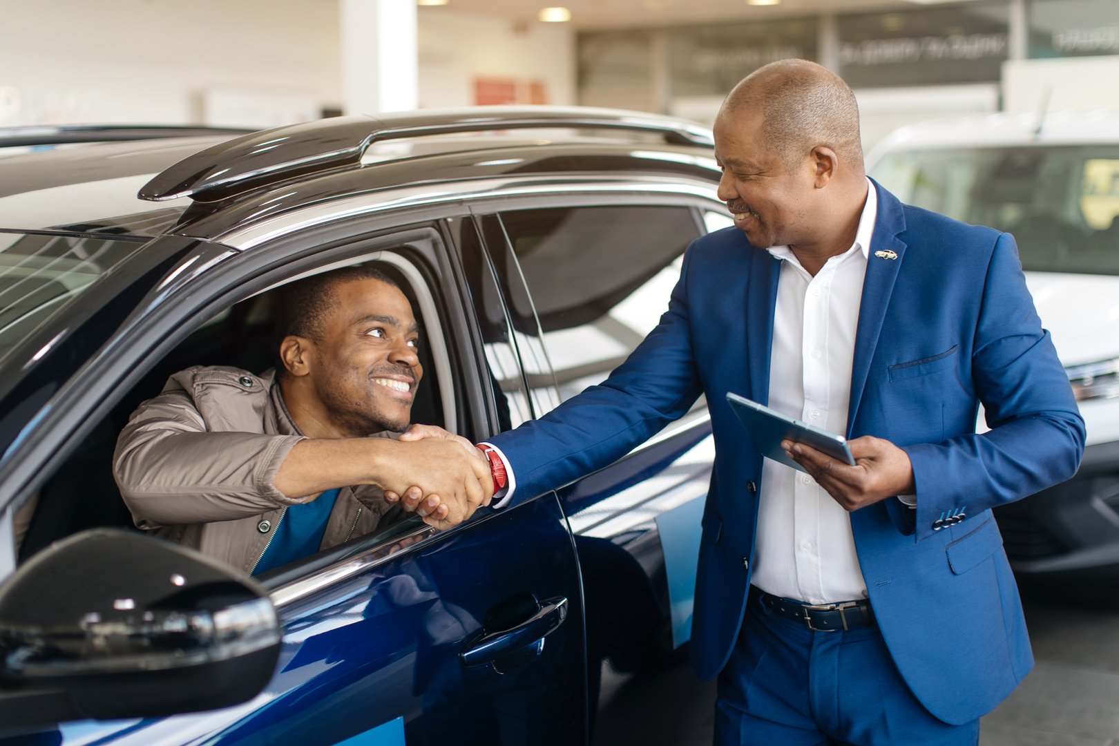 Car Seller Shaking Hands With Buyers After Successful Deal Selling Auto In Dealership Center. Selective Focus. High quality photo