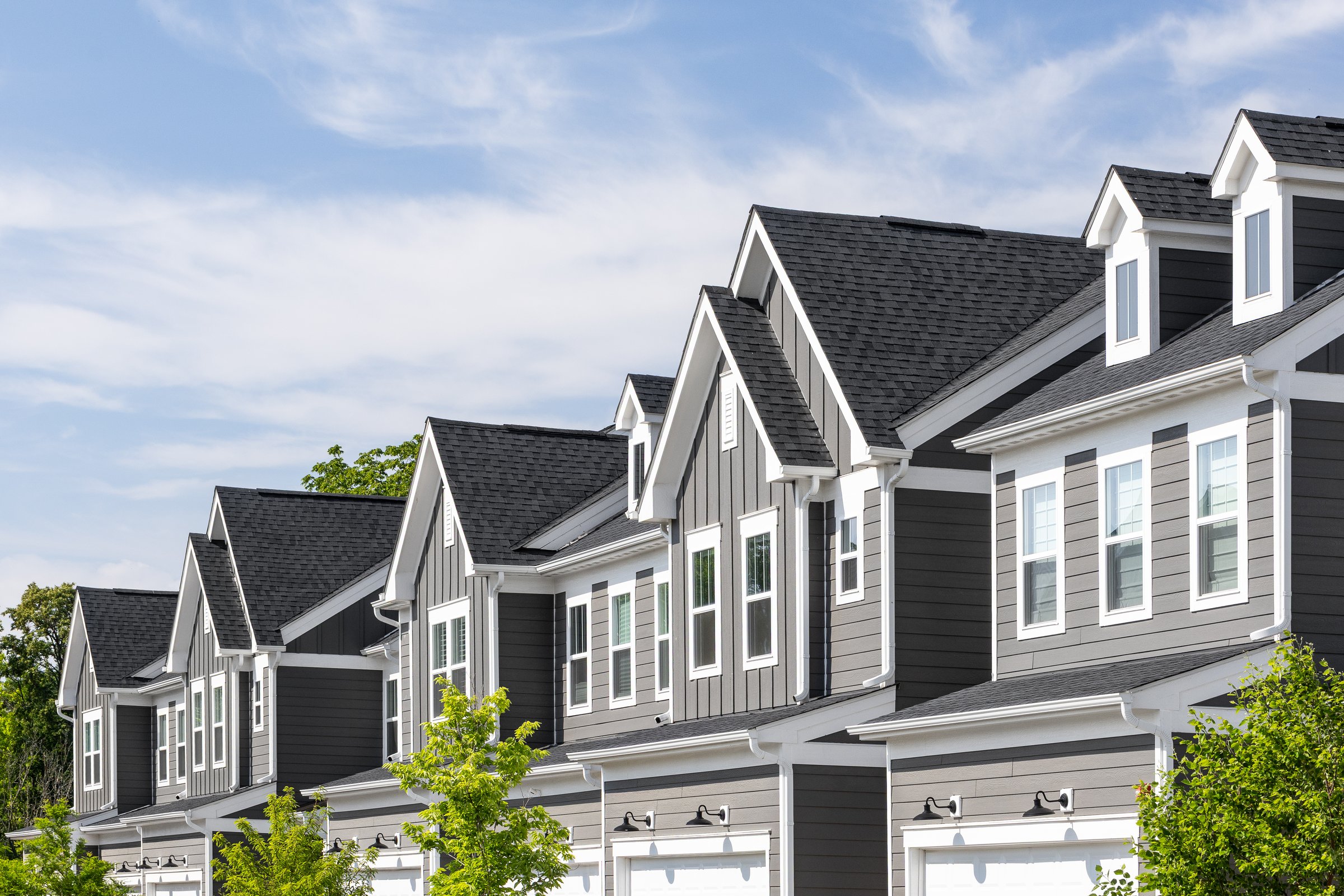 Detail of a row of grey and white modern farmhouse townhomes with board and batten and horiztonal siding.