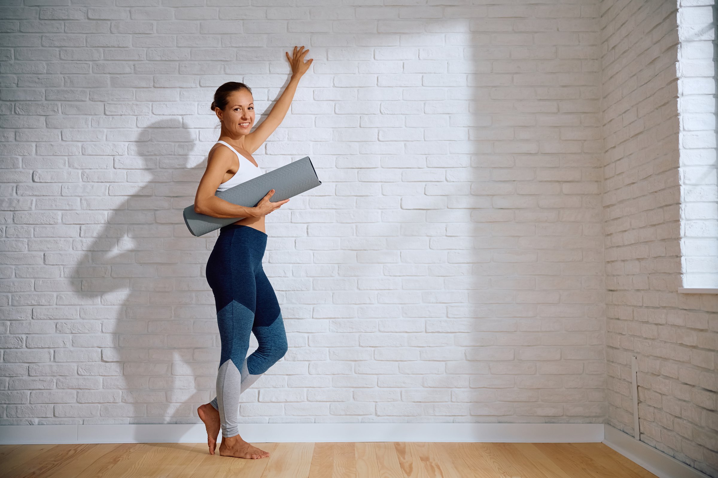 Happy sportswoman standing in Yoga studio and looking at camera. Copy space.