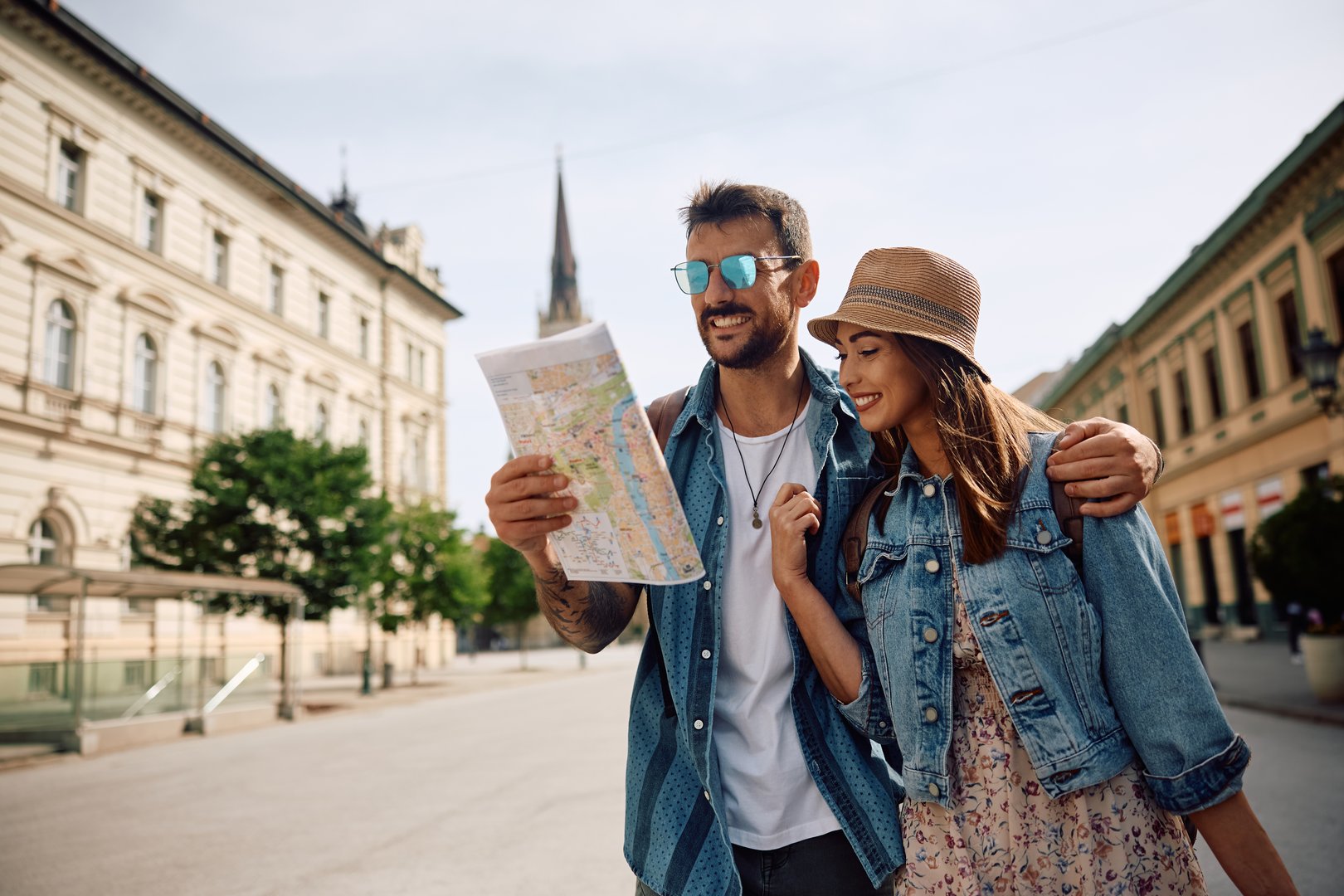 Happy couple of tourists reading map while walking through the city. Copy space.
