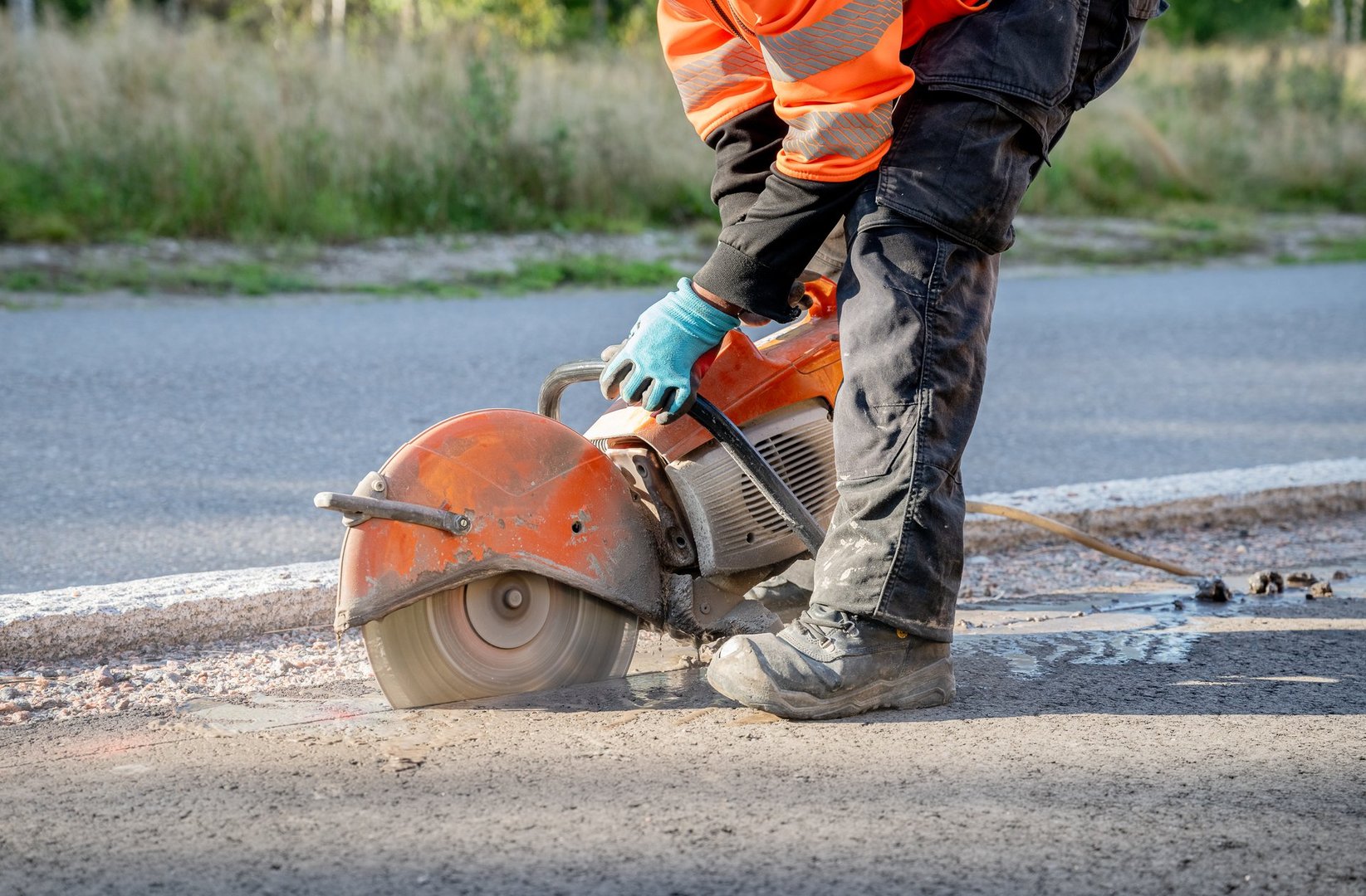 construction worker cuts the asphalt with a circular saw on a road