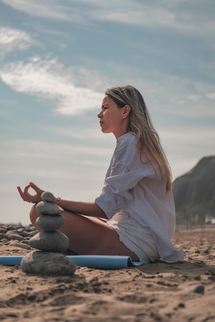 Woman practicing yoga and meditation on the beach, finding peace and mindfulness during summer