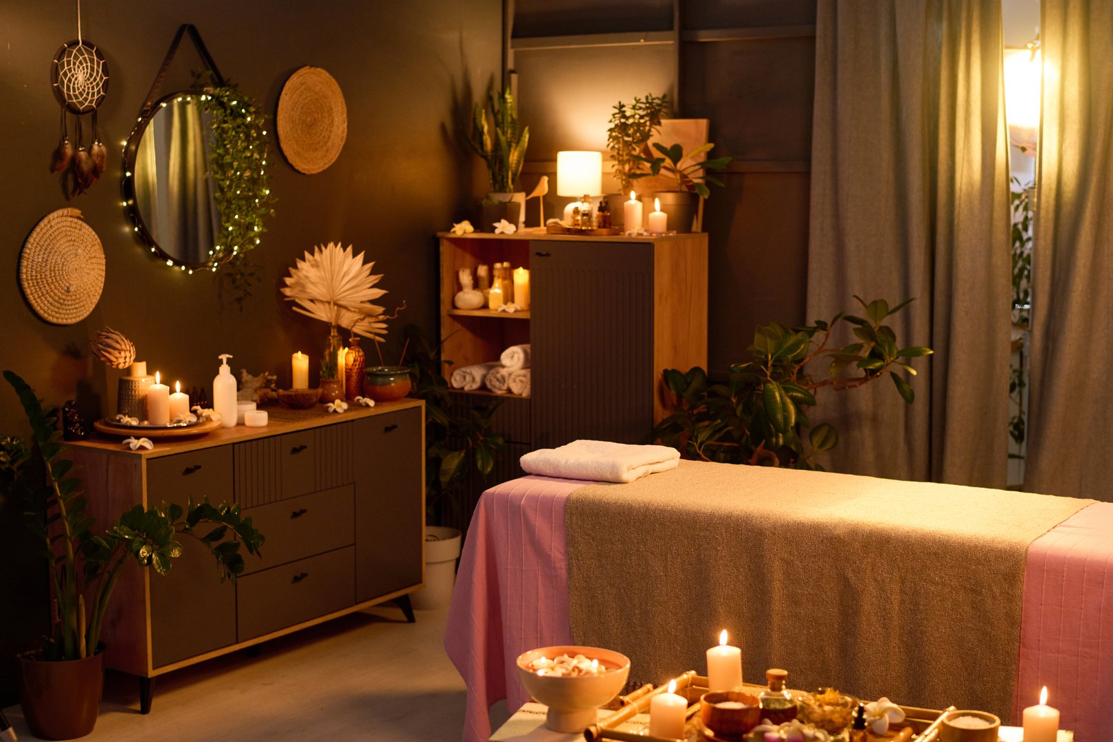 High angle shot of spacious dimly lit room with aroma candles, incenses and massage table in center