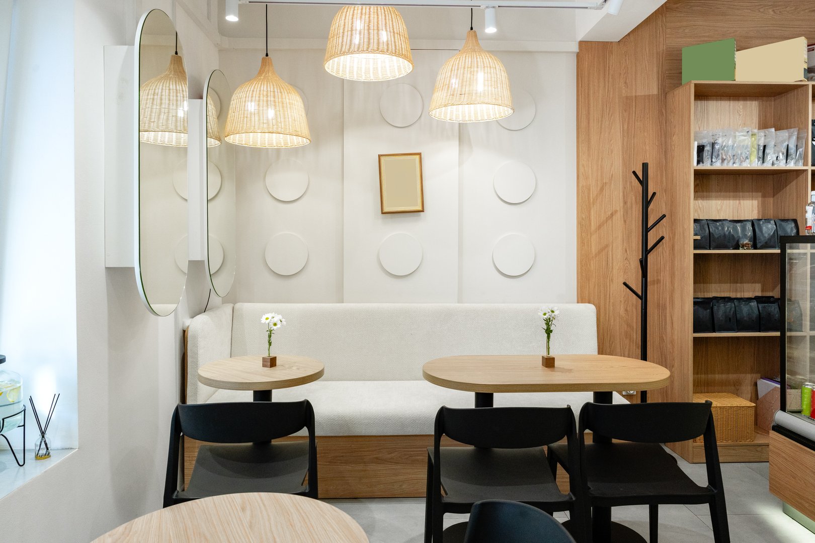 Two wooden tables are set in a stylish cafe featuring soft lighting and a welcoming vibe.