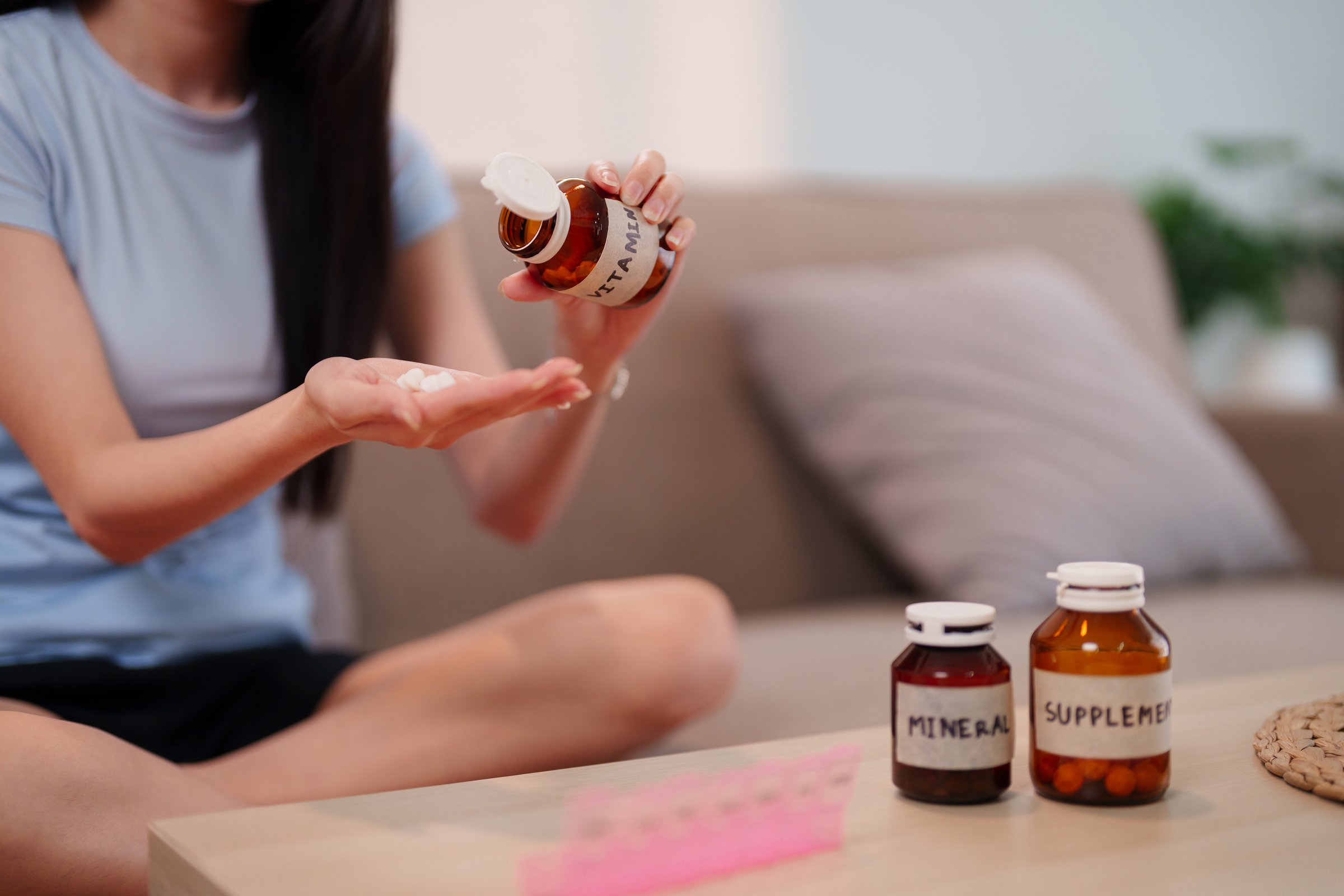 A person demonstrates proactive health practices by taking essential daily supplements promoting wellbeing and long life at home