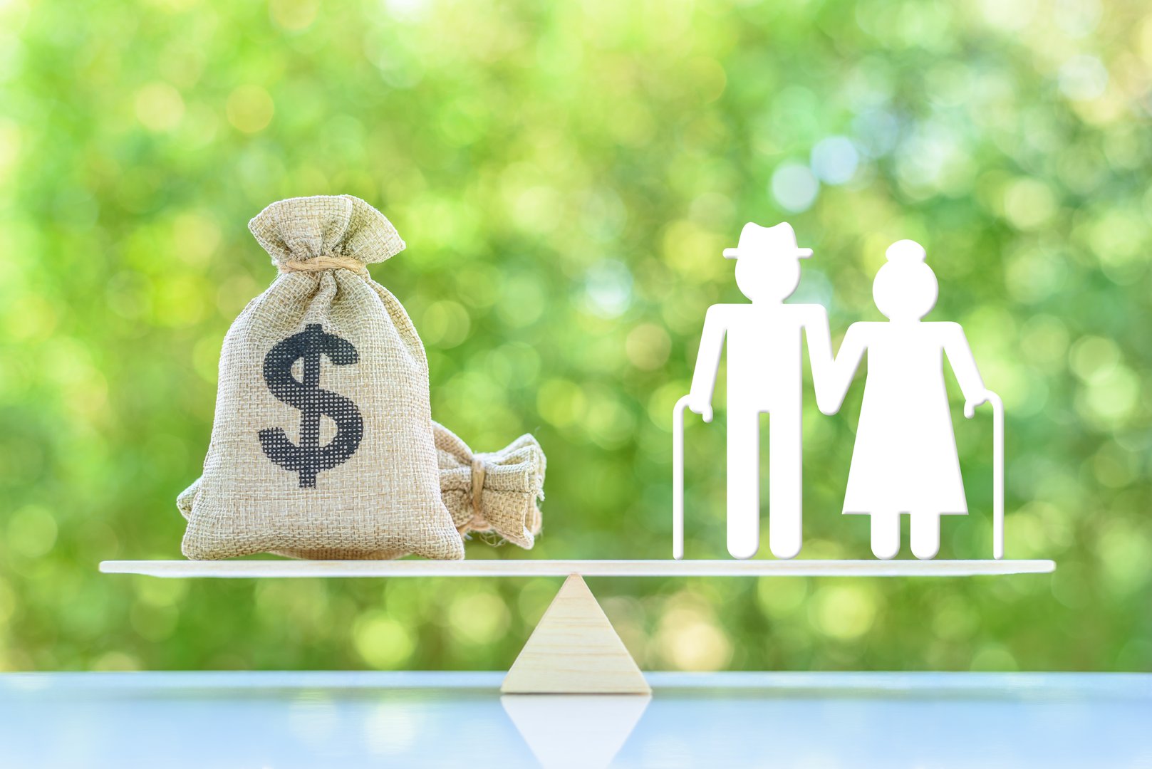 Financial Planning for Seniors : Balancing Retirement Income and Expenses. A miniature elder couple standing on a basic balance scale with US dollar money bag. Elderly face challenges in retirement.