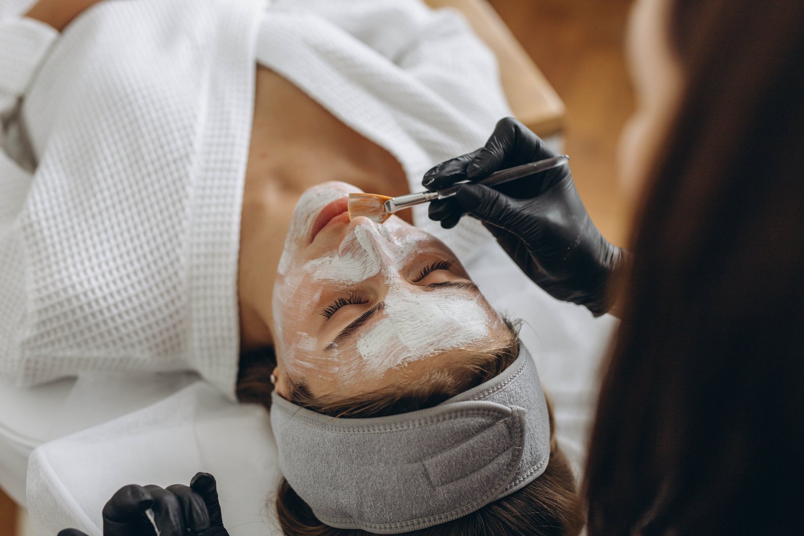 Close up of cosmetologist make face mask for woman client in saloon.Dermatology,beauty concept. High quality photo