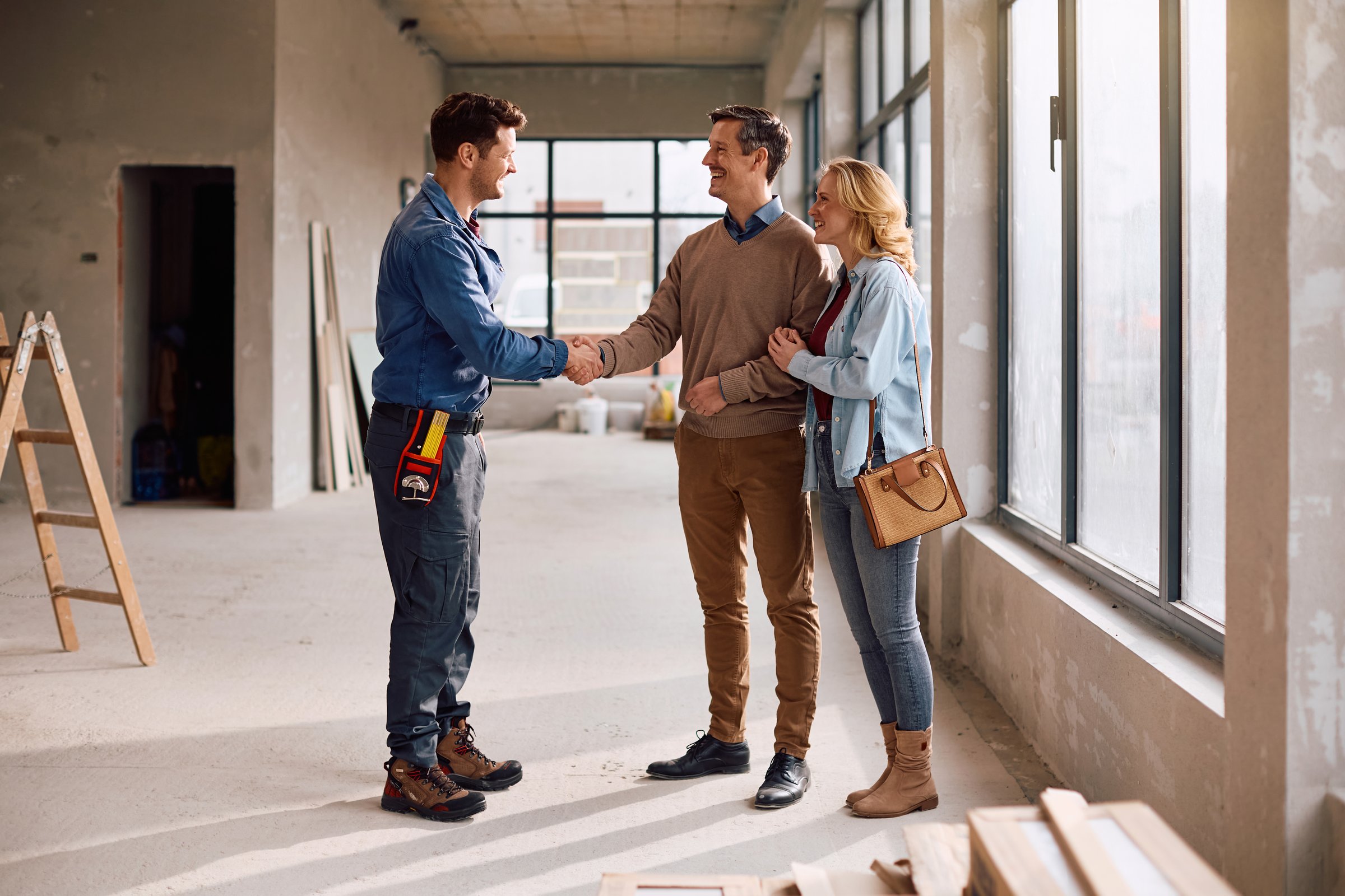 Happy Hispanic construction worker greeting his clients during home improvement project