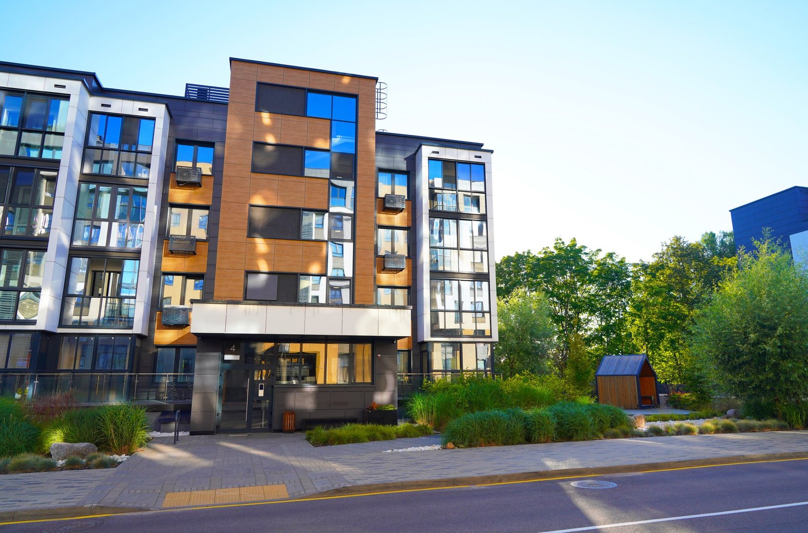 Modern residential building in contemporary architecture. Landscaping for urban spaces. Modern apartment Facade in green environment. Landscape design in Condominium. Entrance to residential building.