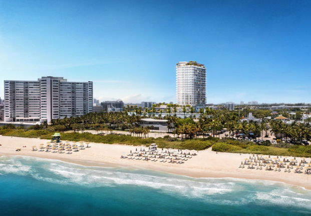 Beachfront view of high-rise buildings with umbrellas and chairs on the sandy shore under a clear blue sky.