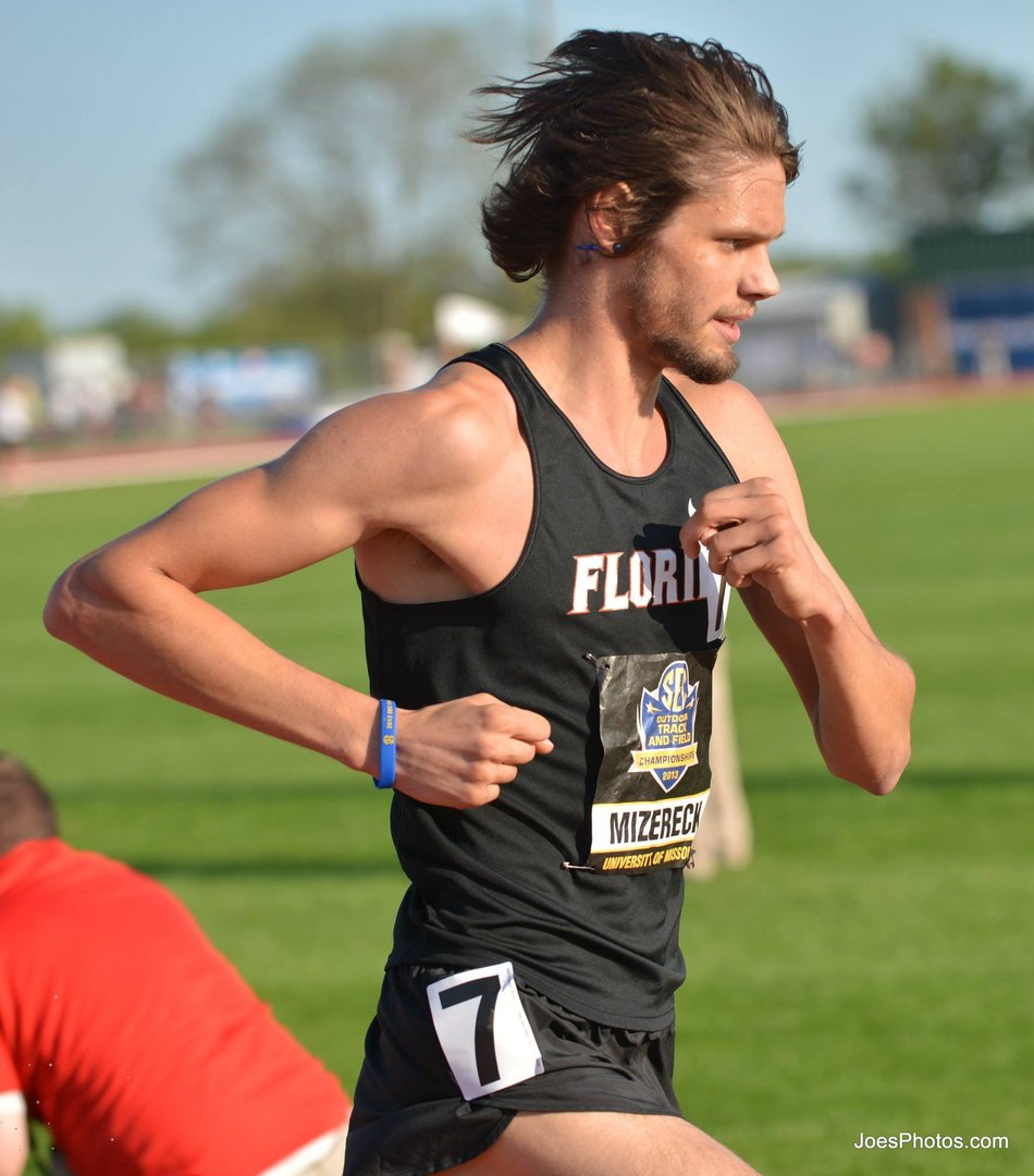 A male athlete running on a track, wearing a black Florida jersey with the number 7 and a SBL race bib.