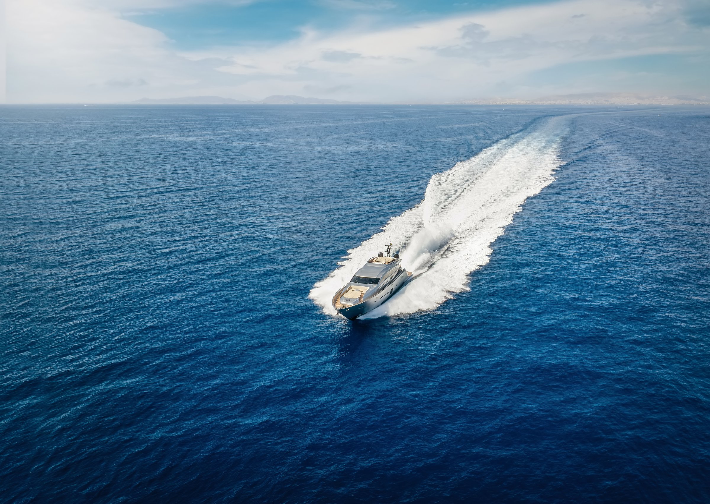 Aerial view of a luxury yacht cruising with speed over blue ocean with copy space