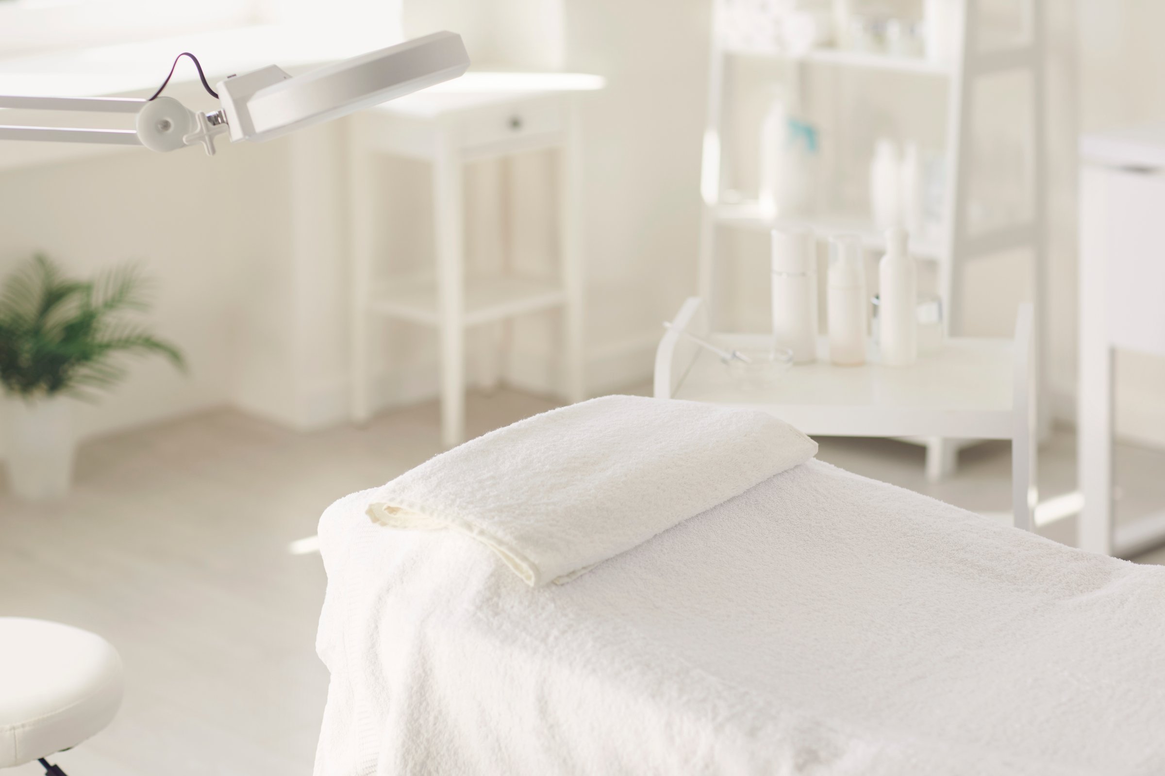 The interior of the beauty salon. Workplace of a cosmetologist maasagist. White dermatologist office. Table with white towel.