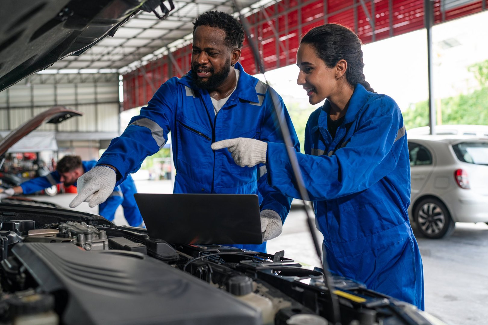 Team Auto mechanic in blue uniform are repair and maintenance auto engine is problems at car repair shop.