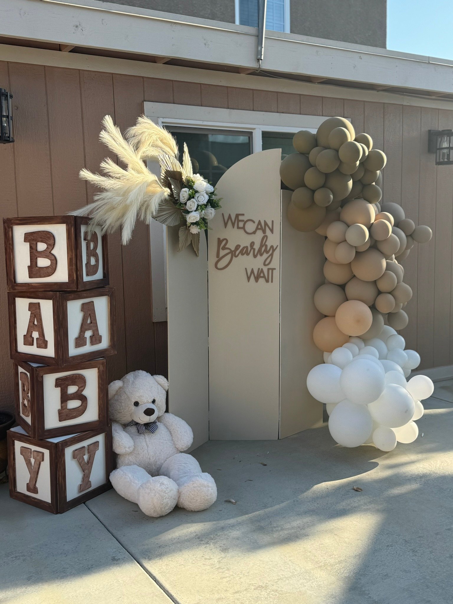 Baby shower decor with teddy bear, balloon arch, blocks spelling BABY, and sign saying We can bearly wait.