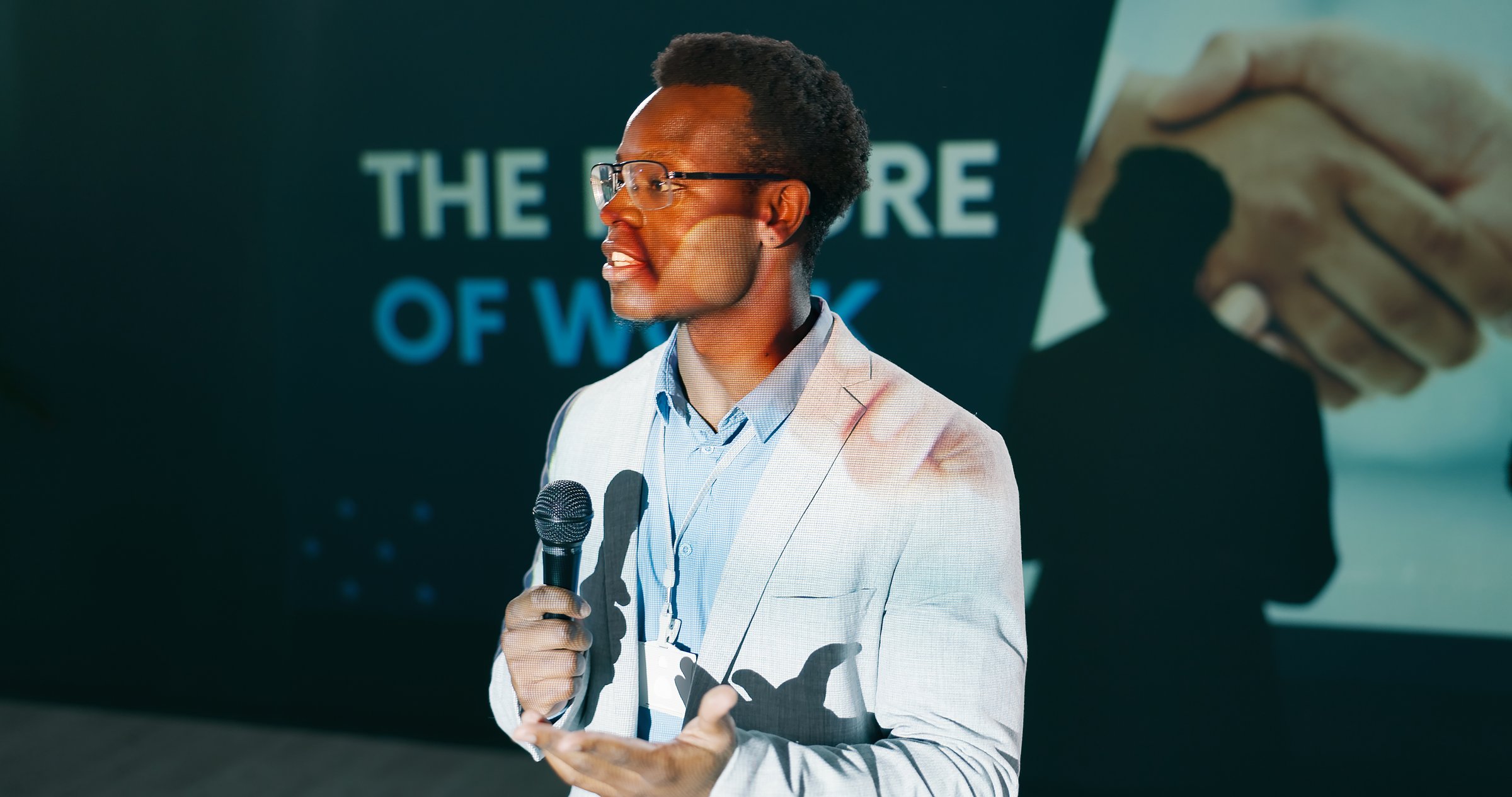 Future, presentation and speech of man with microphone on stage for business or work seminar. Coaching, development and training with African speaker on stage for conference or public speaking