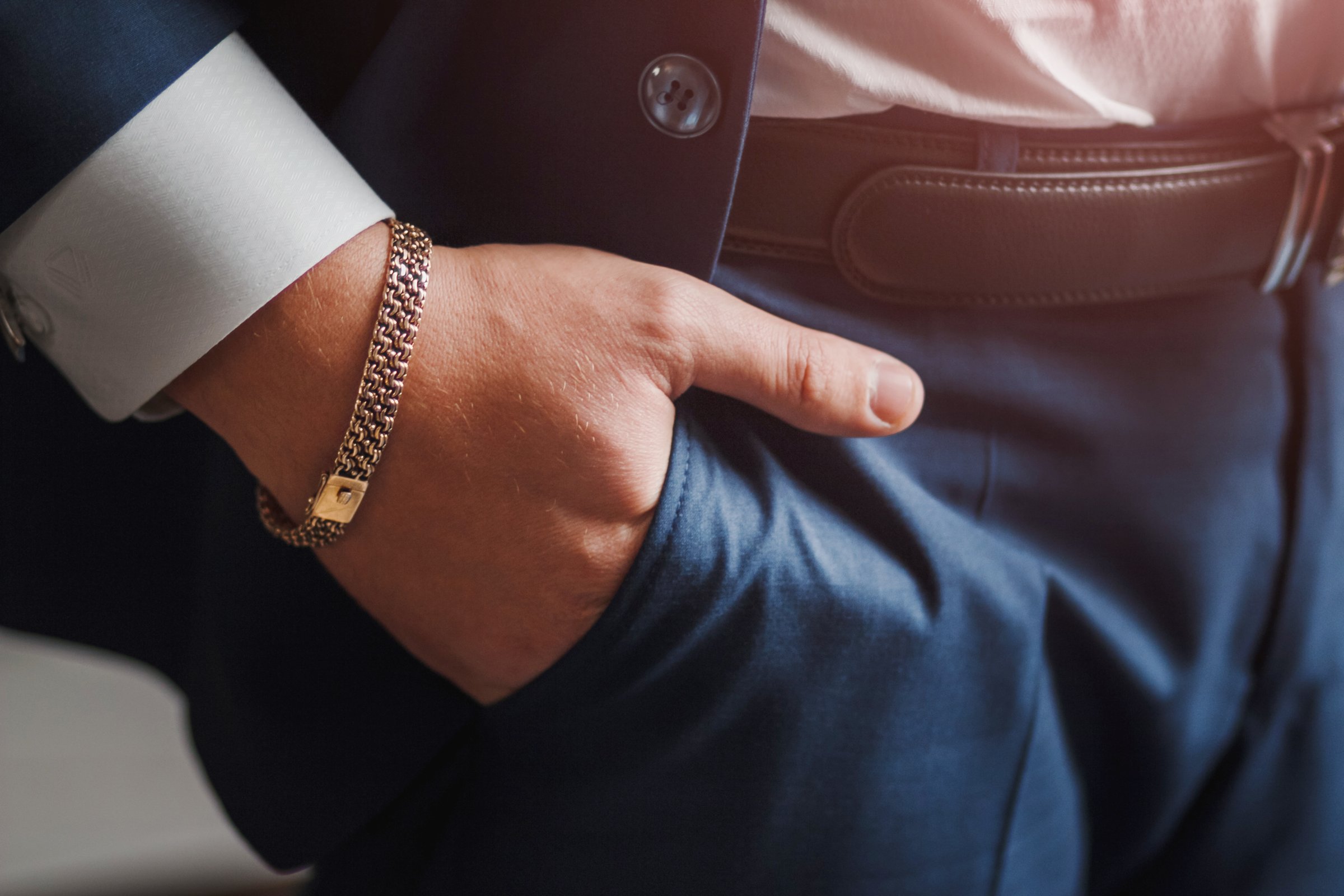Business man's hand with gold chain jewelry in pocket
