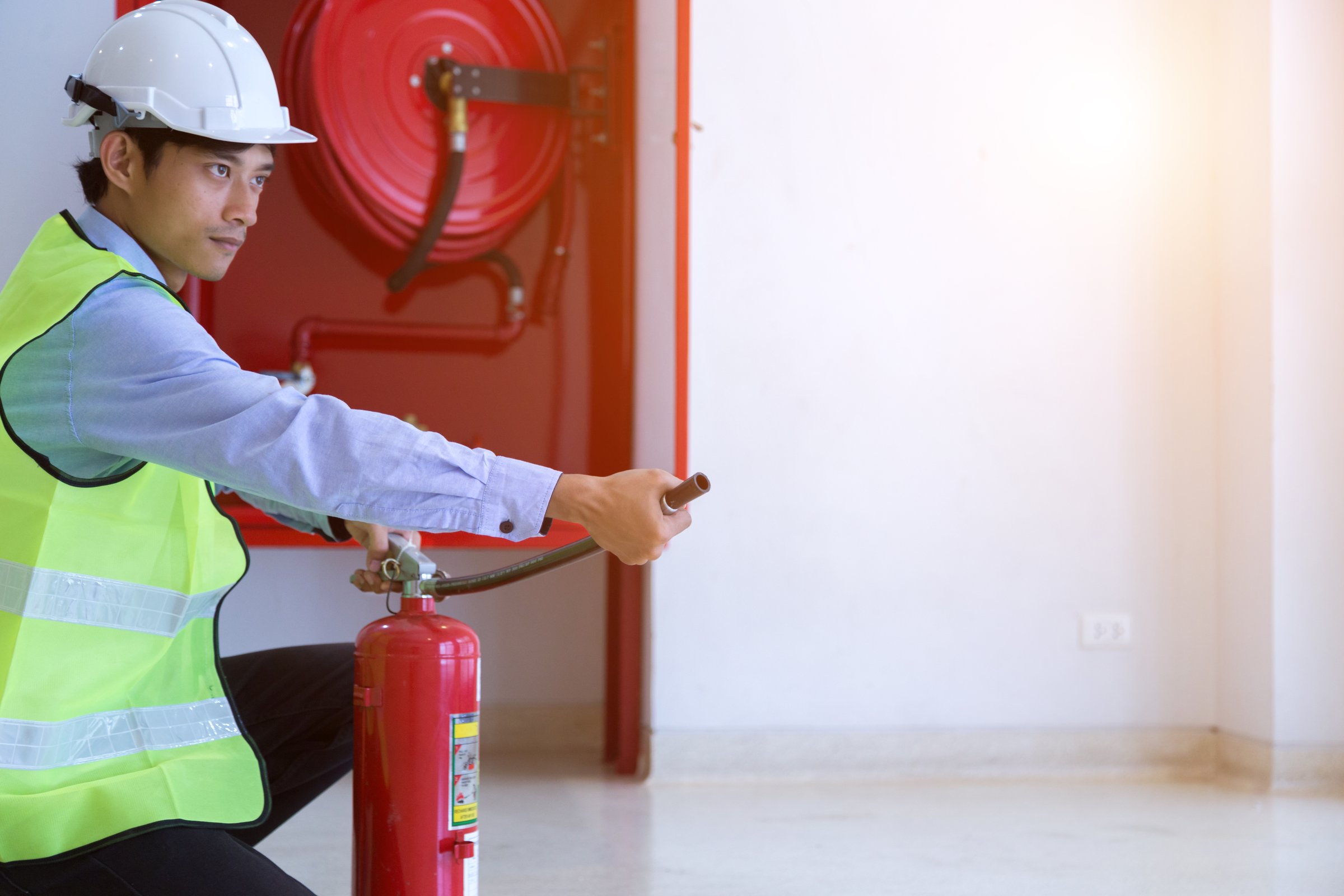 Male Professional checking a fire extinguisher.