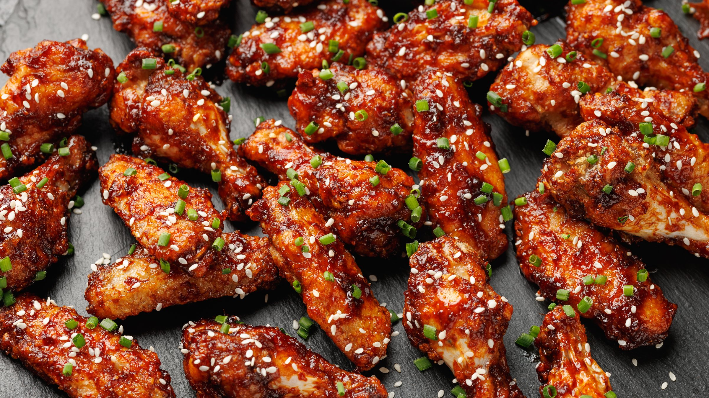 Spicy korean chicken wings with sesame seeds and chives.