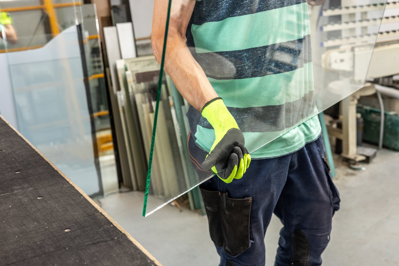 A glazier in a glass factory holds a large piece of glass in his hands, The concept of craftsmanship and industry, Working with glass