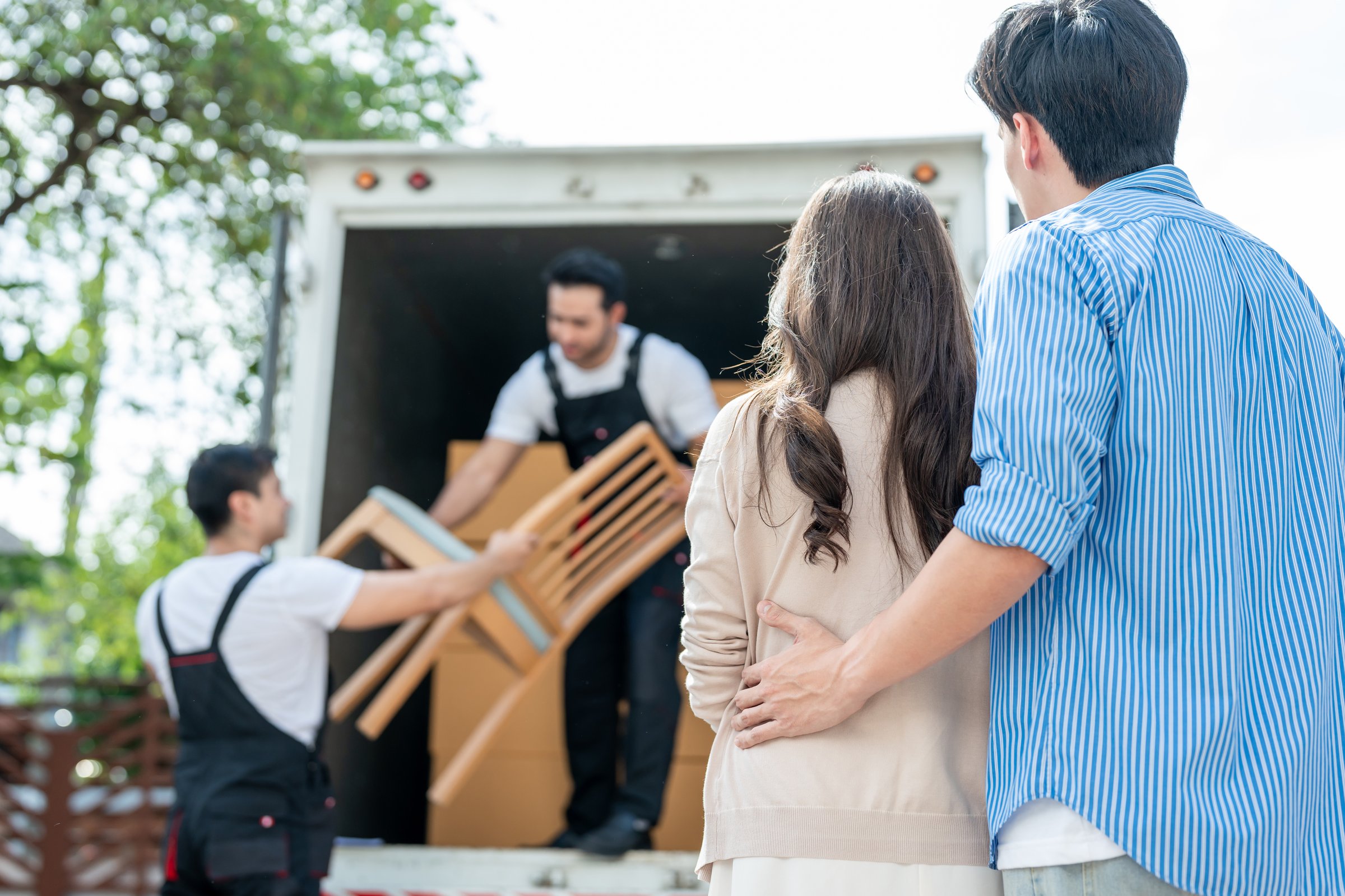 Caucasian delivery man worker delivering package to young couple in house. Attractive courier employee working and deliver box cardboard from car truck infront of new house of new marriage partner.