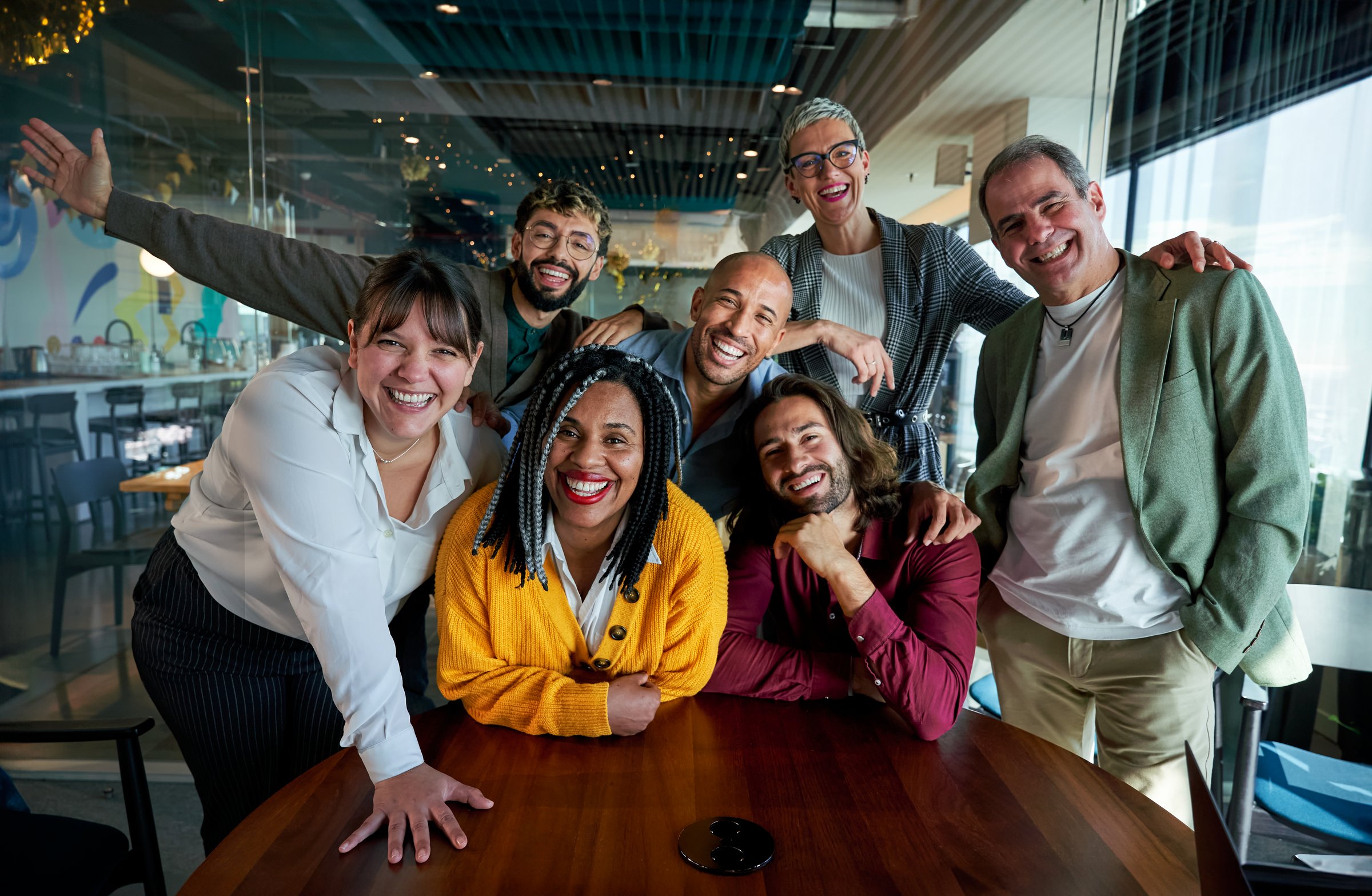 Happy portrait of diverse businesspeople smiling and posing together in a modern office space, showing teamwork and unity, looking at the camera cheerfully.