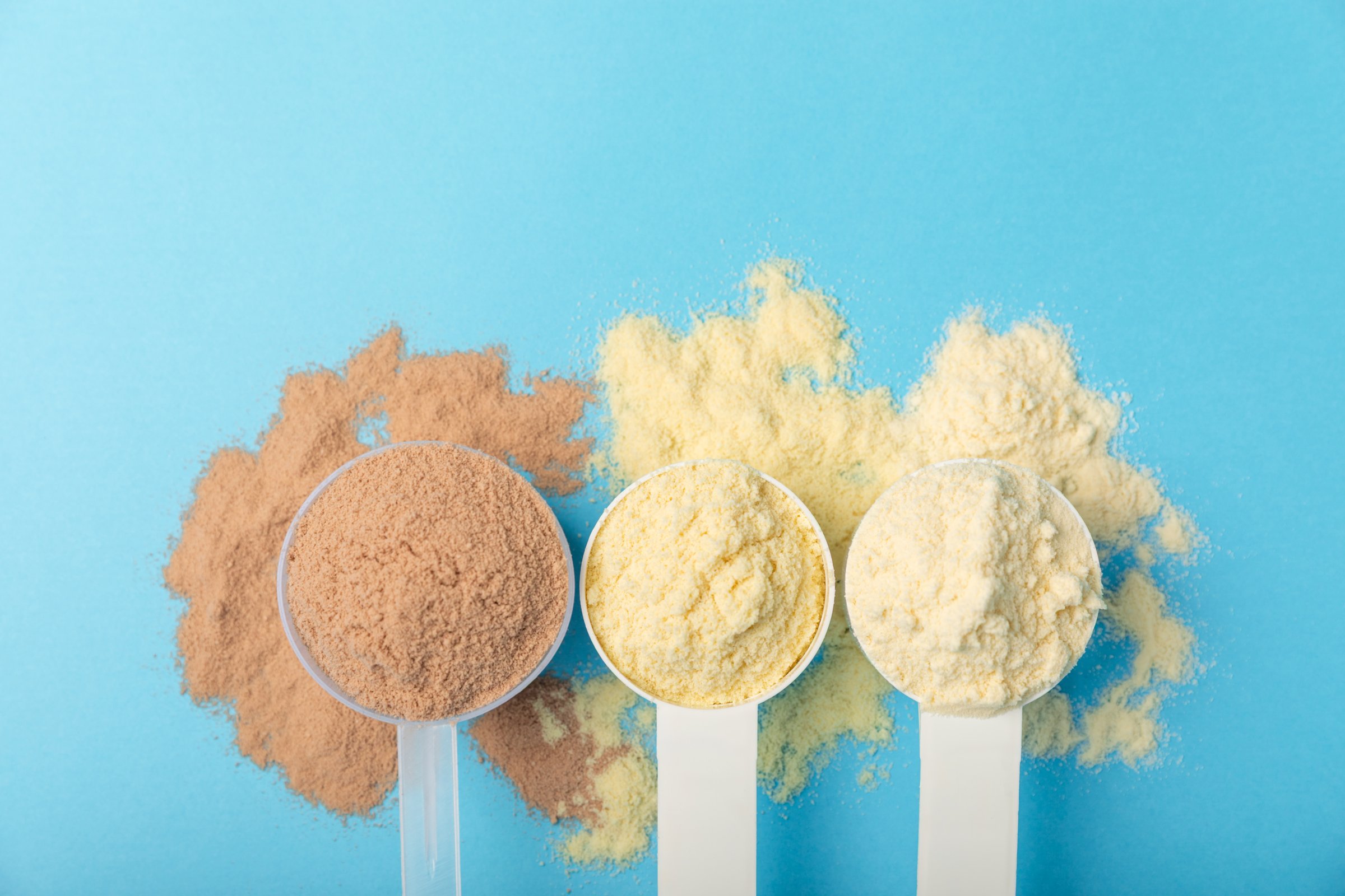 Protein powder. A spoonful of protein powder on a table. Different flavors of whey protein powder. Sports nutrition concept. Gym. Amino acid food supplement, creatine powder. Copy space