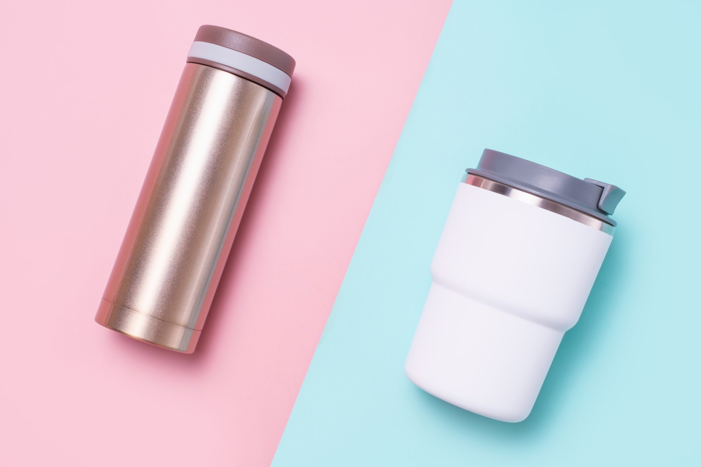 Two thermo mug and thermos on a blue and pink background, top view close-up