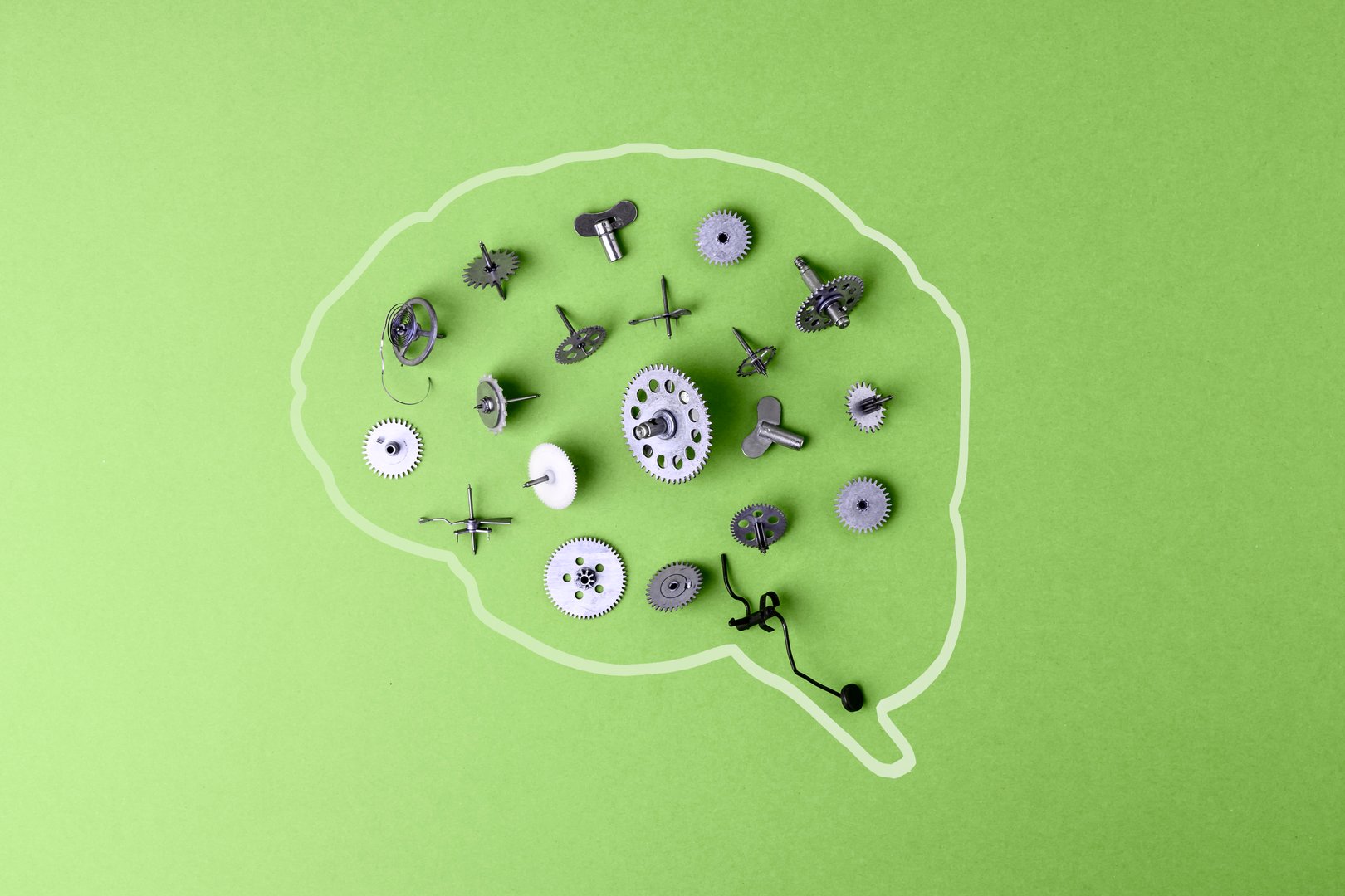 A brain outline on a green background filled with scattered metallic mechanisms, gears, and screws. A symbol of thought processes, mental well-being, and intelligence.
