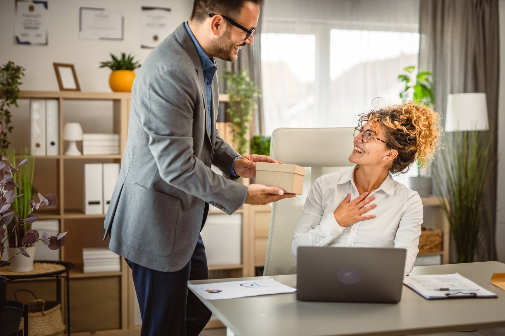 Man colleague bring gift box to his woman colleague at office