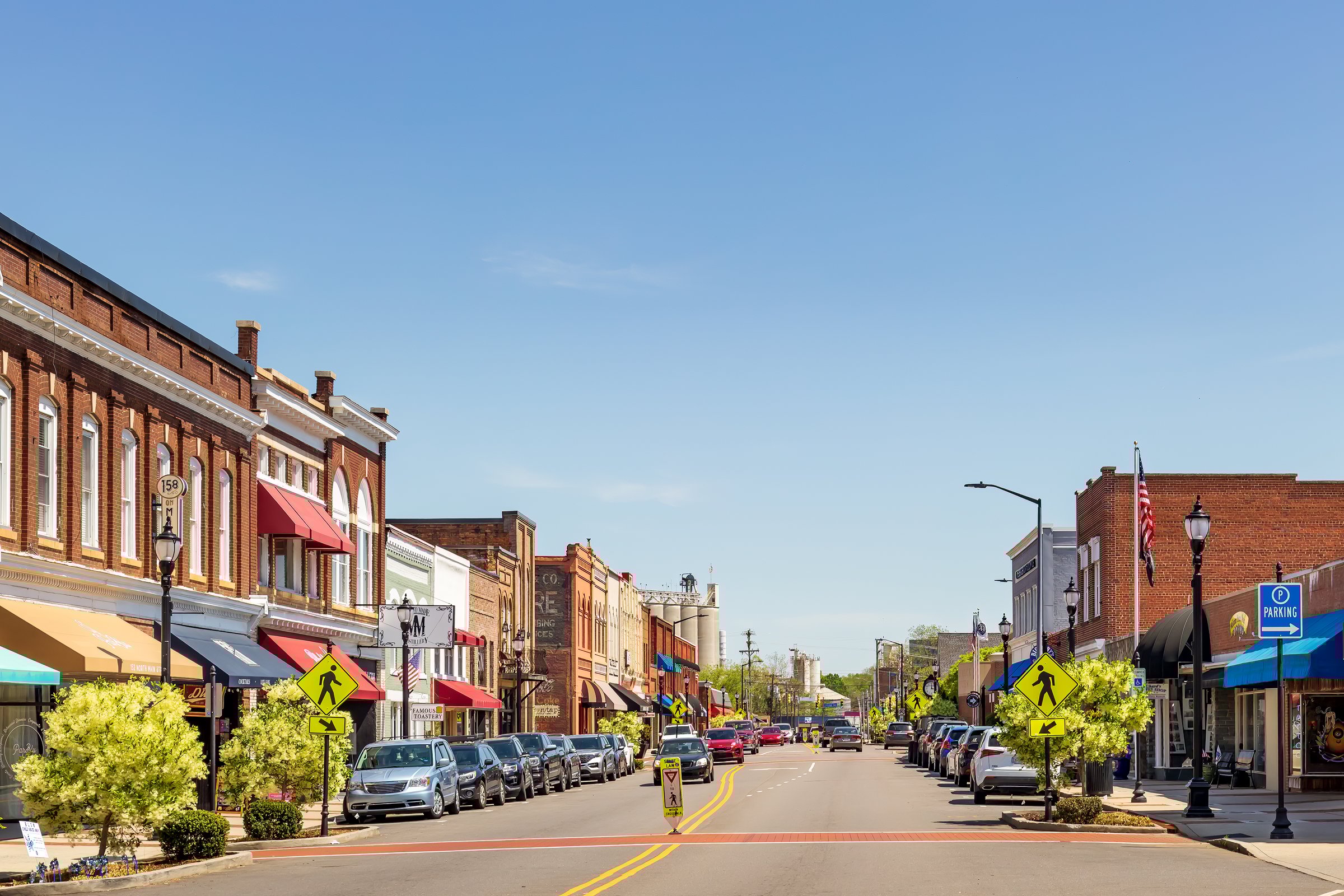 Mooresville, NC, USA-17 April 2022: Iconic, colorful wide-angle Main Street view on a sunny, blue sky, spring day.   Looking toward Bay State Milling Co.