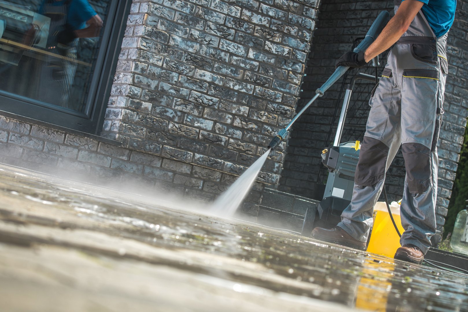 Men Washing Driveway Using Pressure Washer. Spring Time Cleaning.
