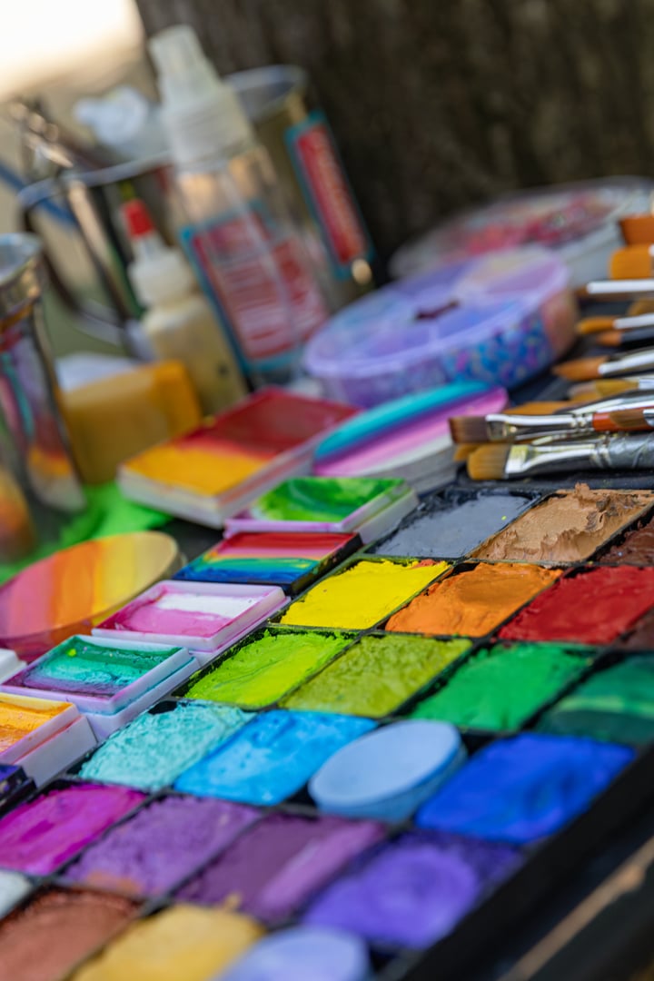 Vibrant palette of face paints and brushes ready for application at an outdoor event