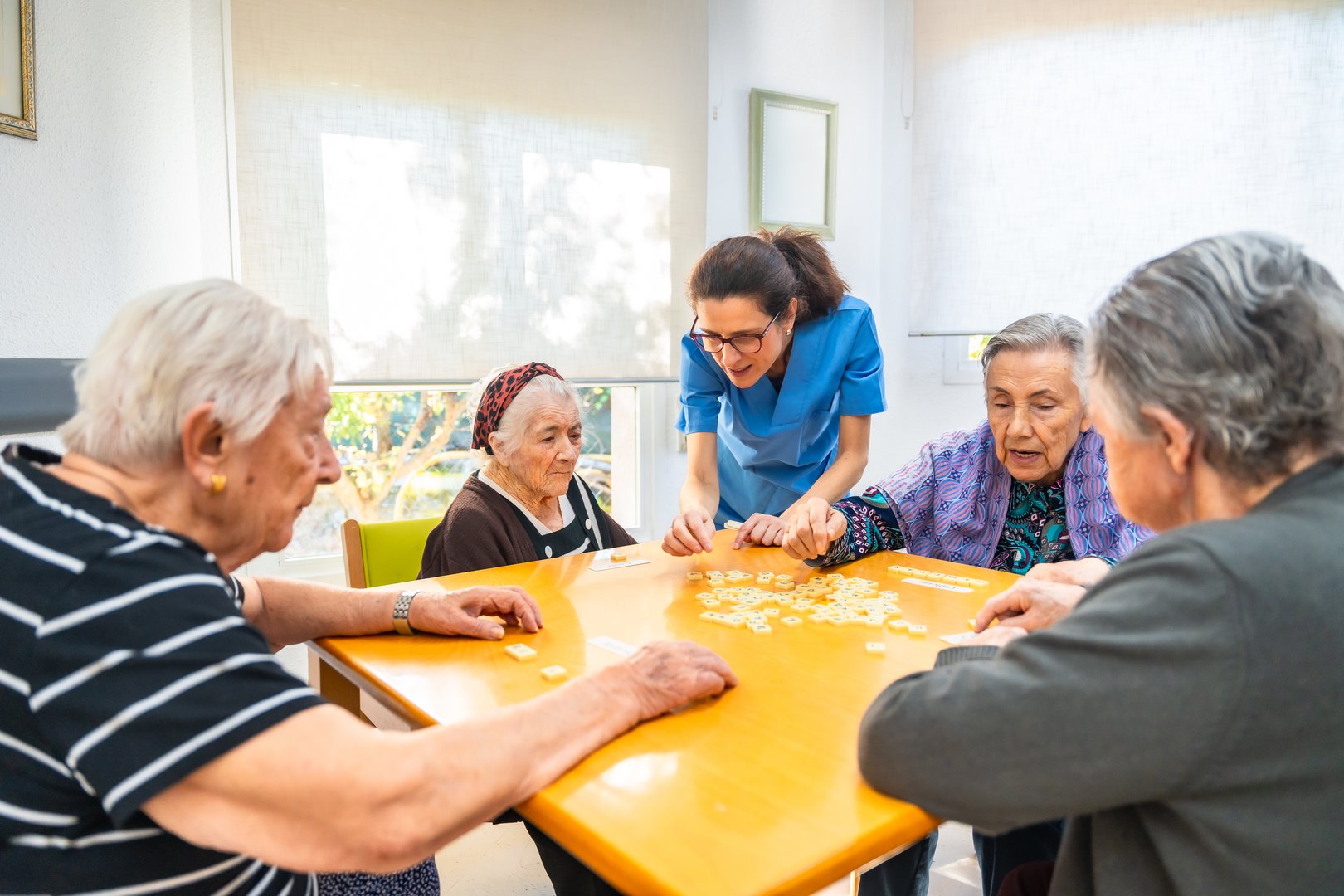Female caucasian nurse and senior people playing board skill games in the nursing home