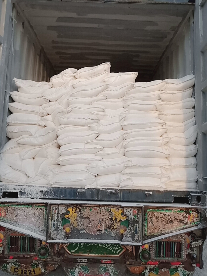 Stacks of white bags loaded into the back of a truck, viewed from the open rear gate.