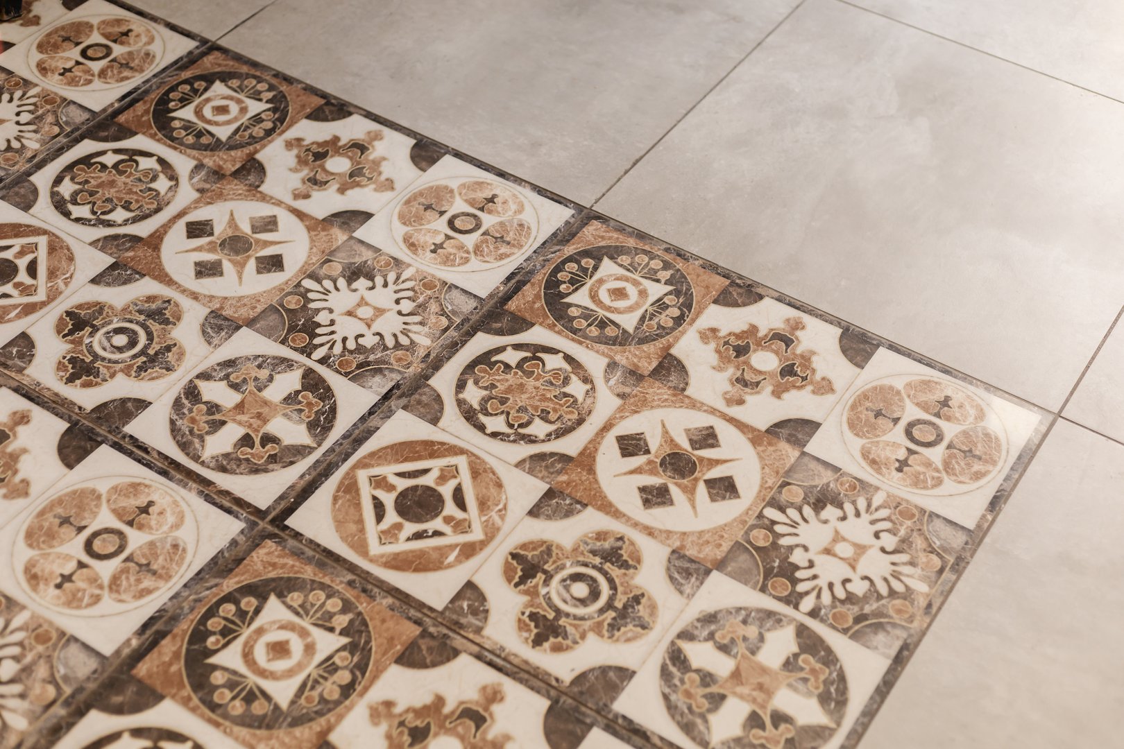 Beautiful ceramic tiles cover the floor, showcasing a mix of patterns in warm colors. The design integrates vintage aesthetics into a contemporary space, creating an inviting atmosphere.