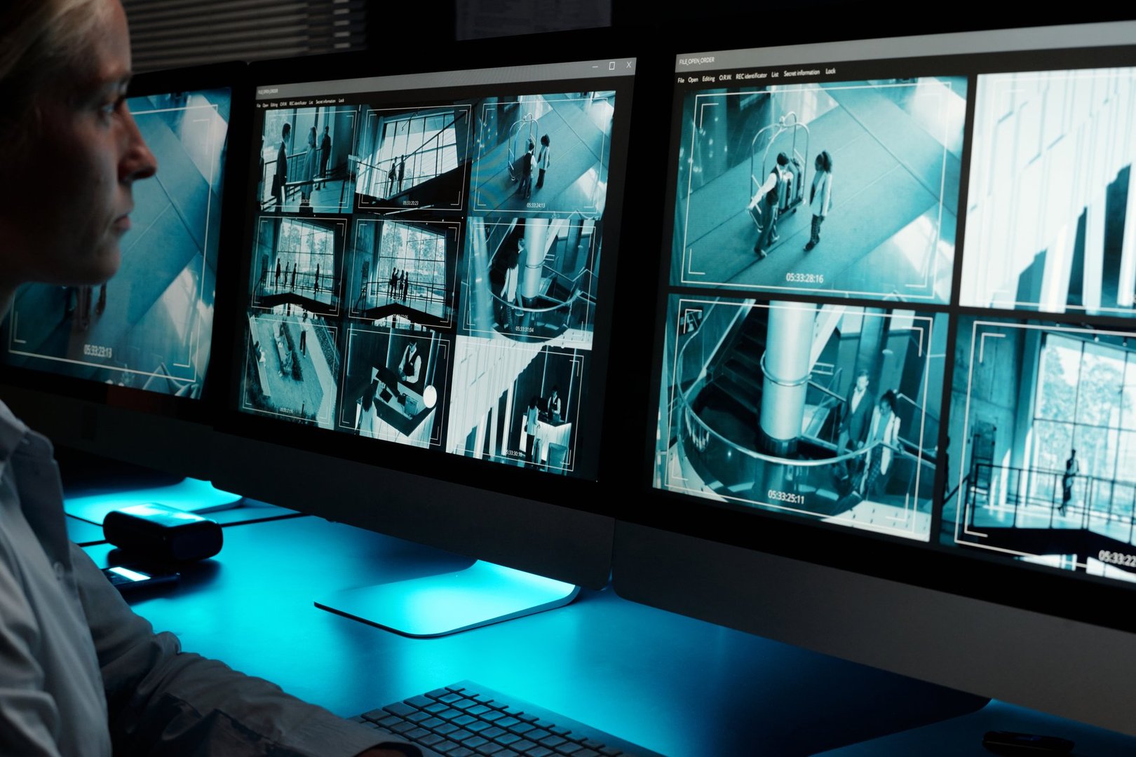 Focus on desktop computer monitors with cctv video system on screens standing in front of young working female guard