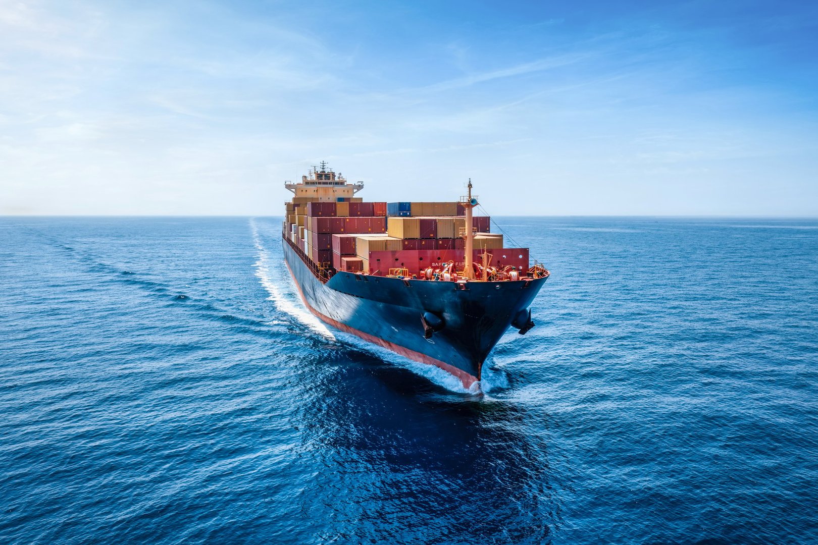 Aerial front view of a industrial container cargo ship traveling over the calm ocean
