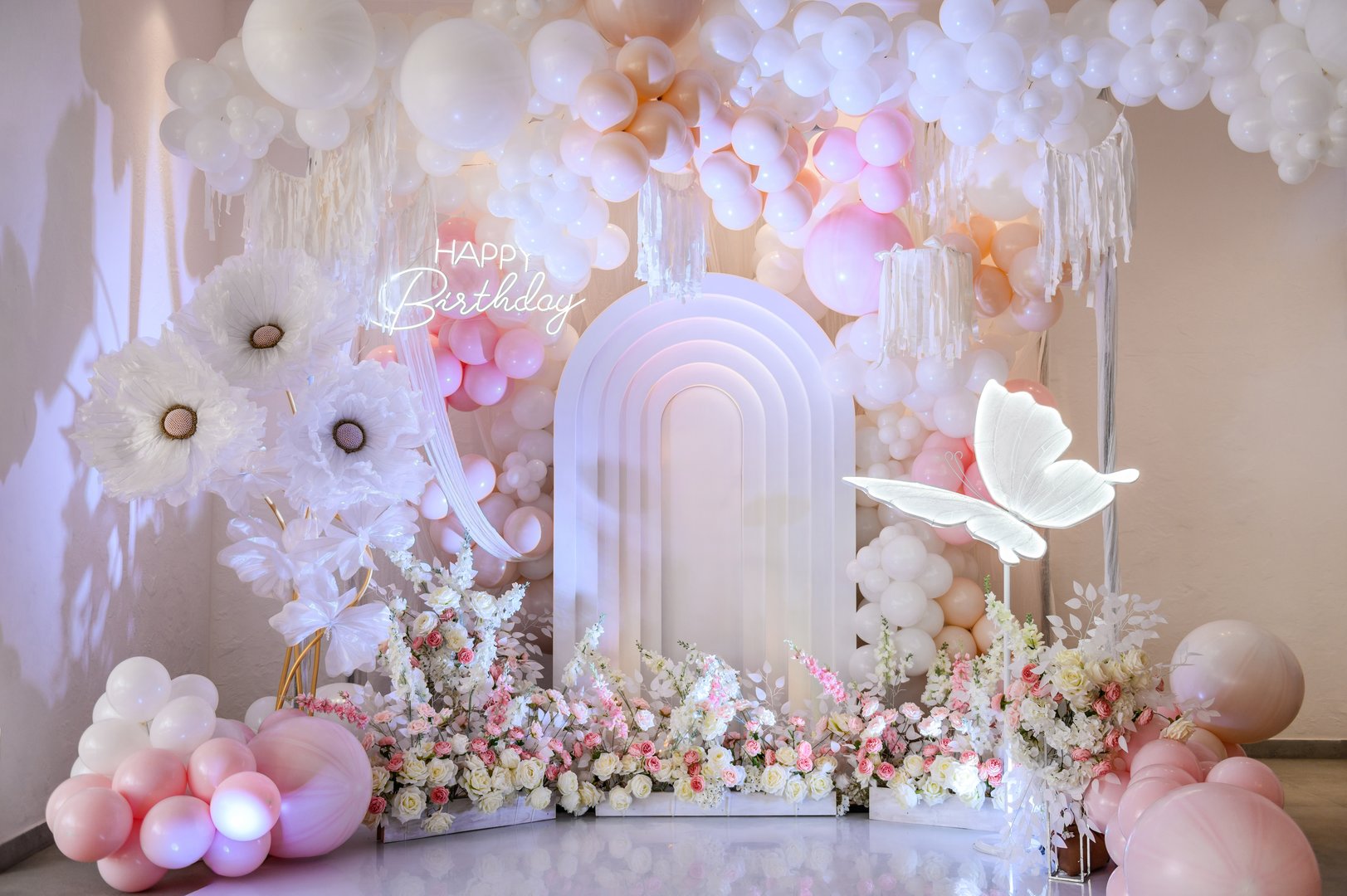 Arch decoration pink, white balloons, text Happy Birthday, decorated flowers. Children's photo zone. Decor paper butterfly. Birthday party for baby girl on a background photo wall.