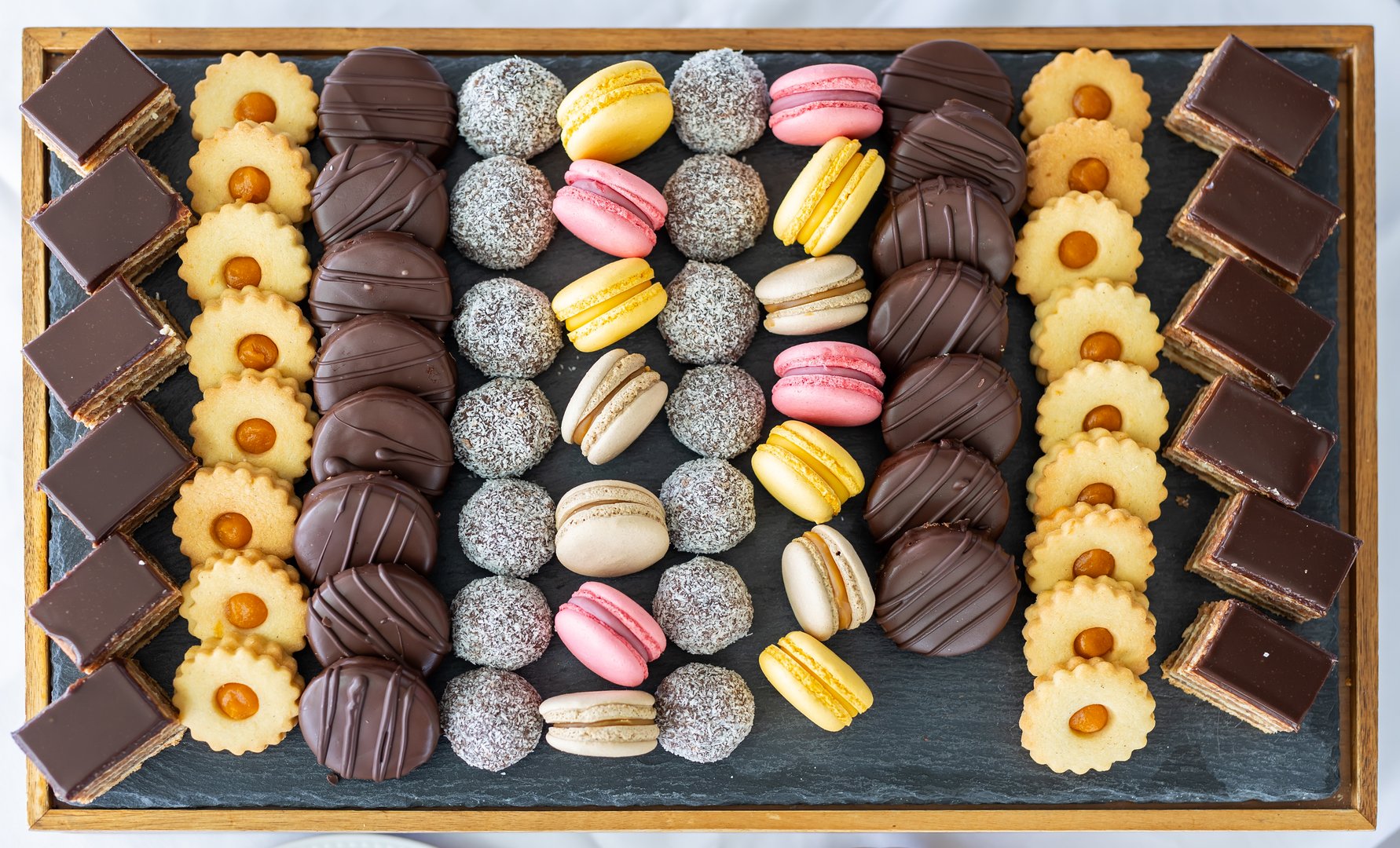 Macarons, chocolate cake and coconut balls in order on plate