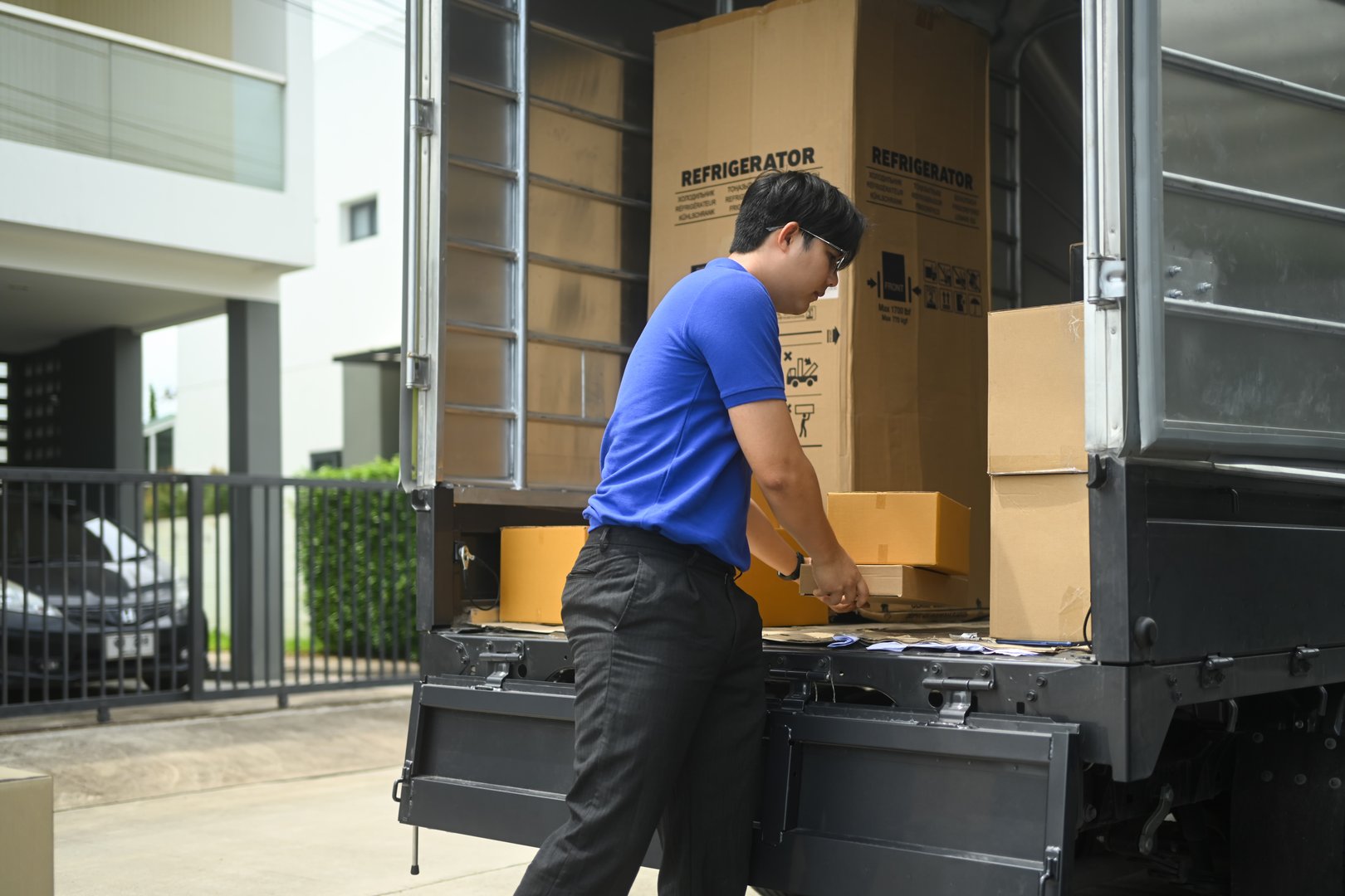 Delivery man unloading parcels from the back of delivery truck. Shipping, logistics and transportation concept.