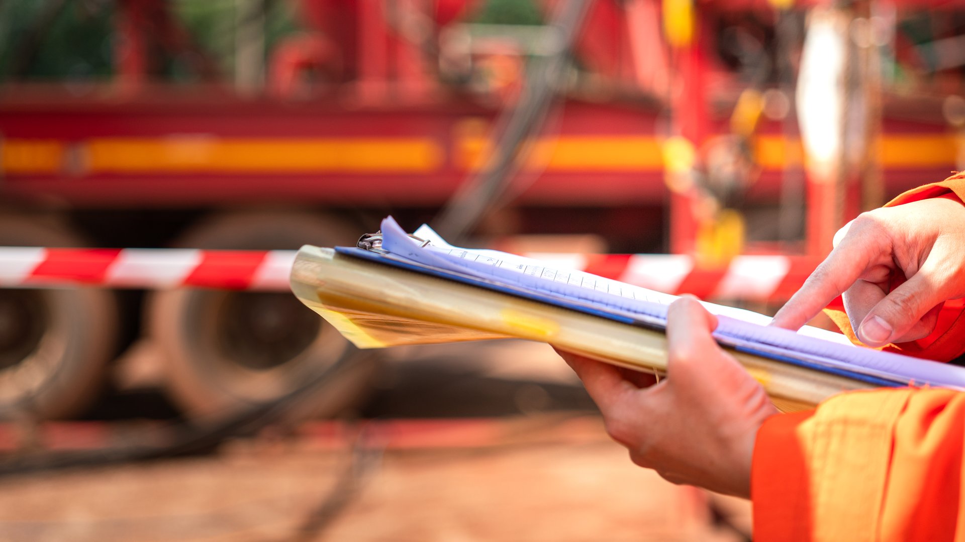 Action of a safety supervisor is review on the document paperwork during perform safety audit with background of the industrial worksite. Close-up and selective focus.