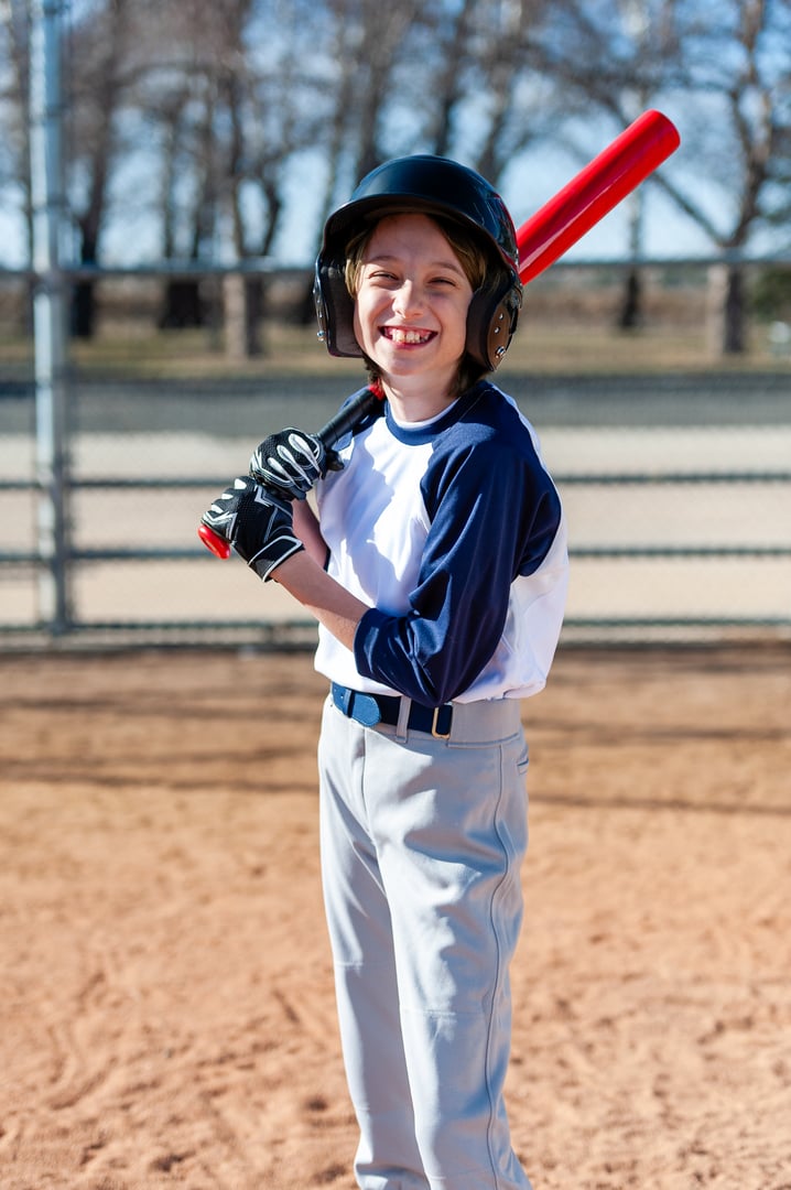 Young girl in little league baseball uniform with bat and helmet at home plate