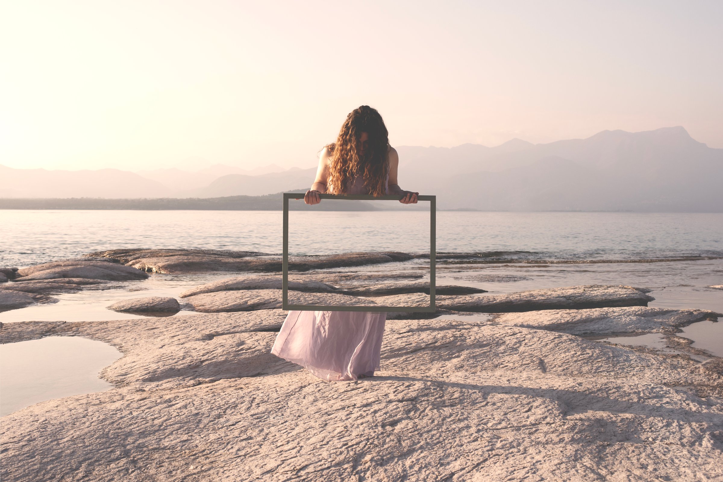 woman holding a frame that surreally reflects the landscape , concept of door to freedom